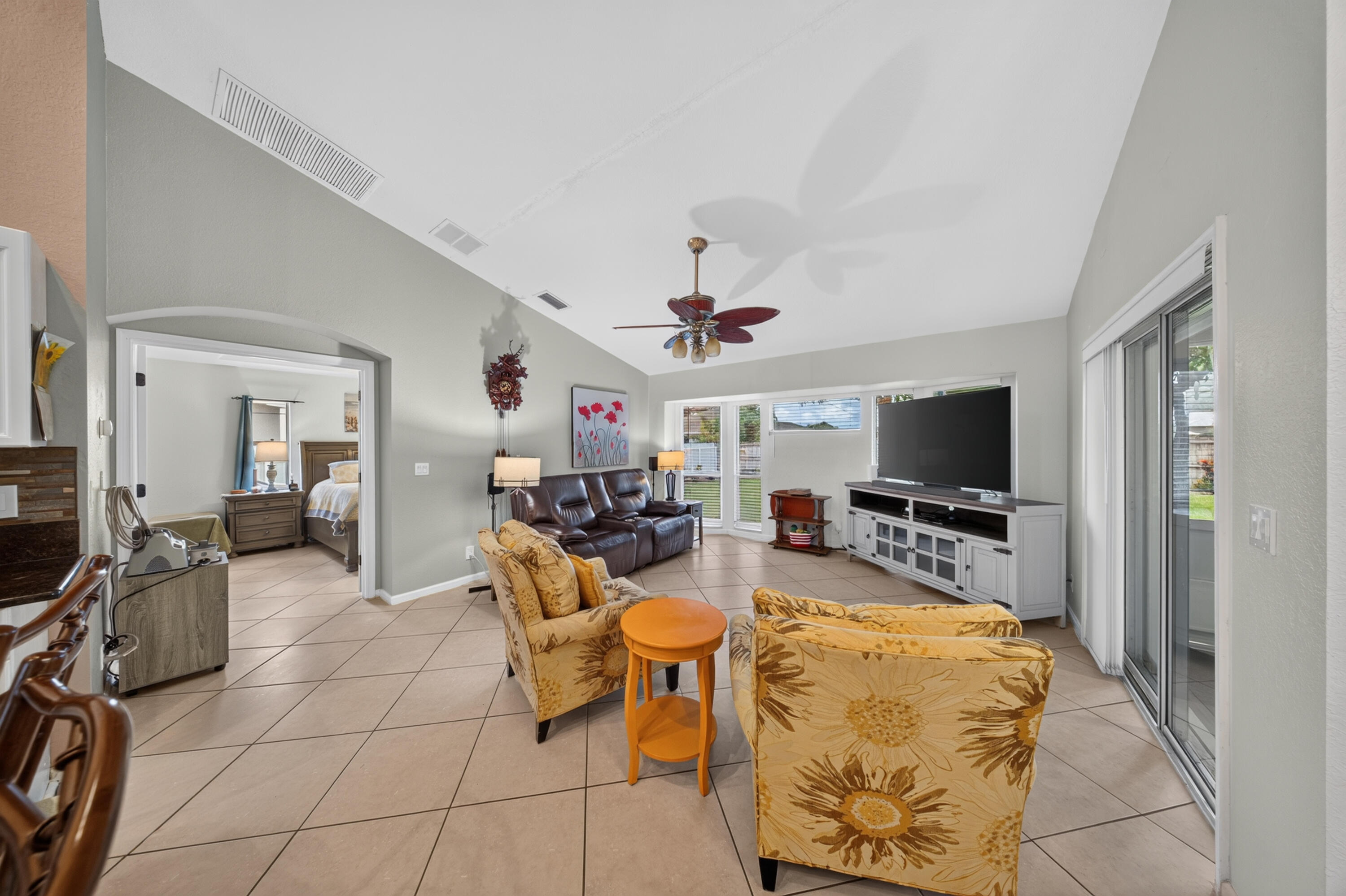 Vaulted ceilings, tile flooring, sliding glass doors, and an arched doorway