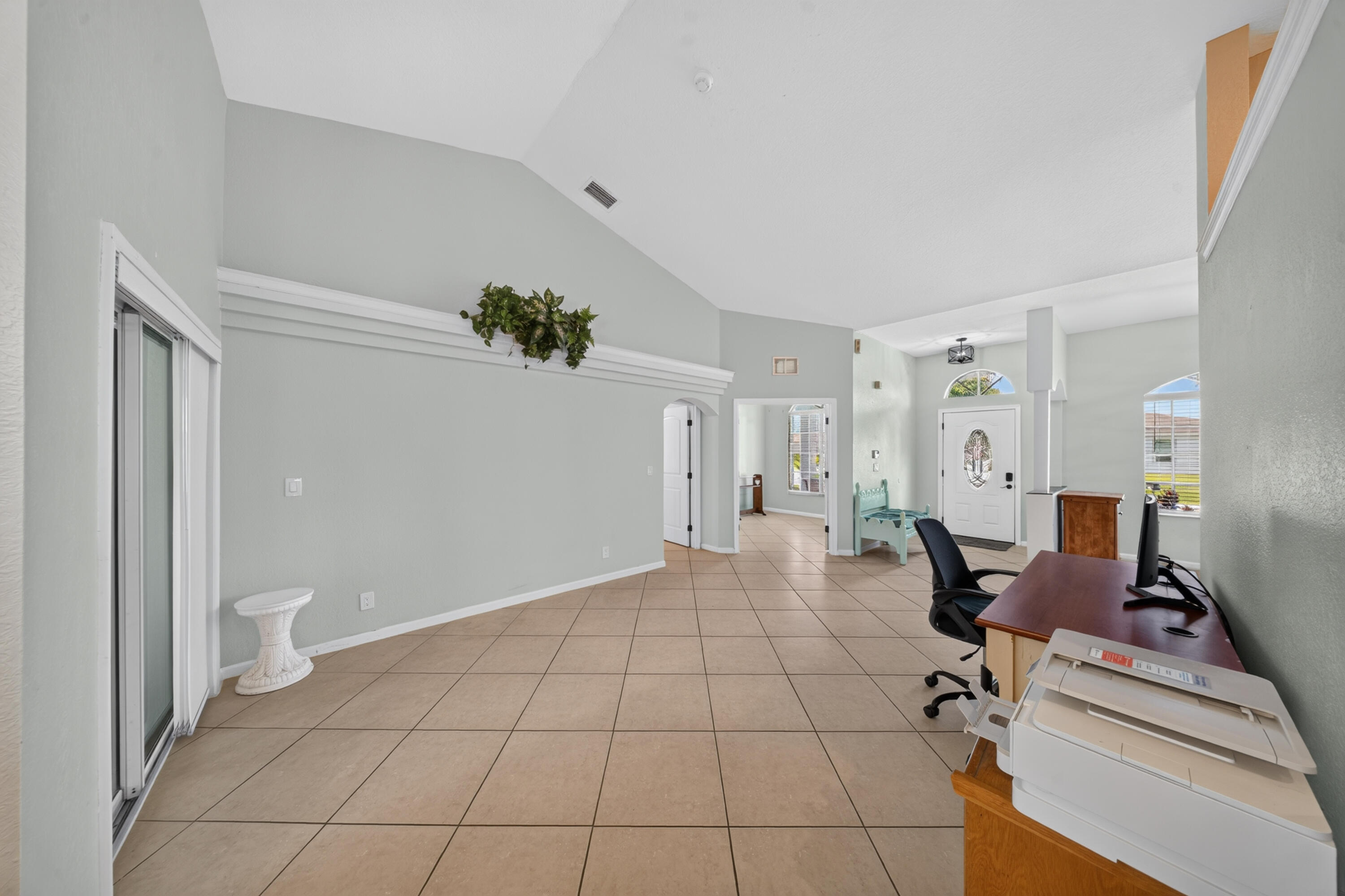Vaulted ceilings, neutral wall tones, ceramic tile flooring, decorative architectural ledge, and sliding glass doors