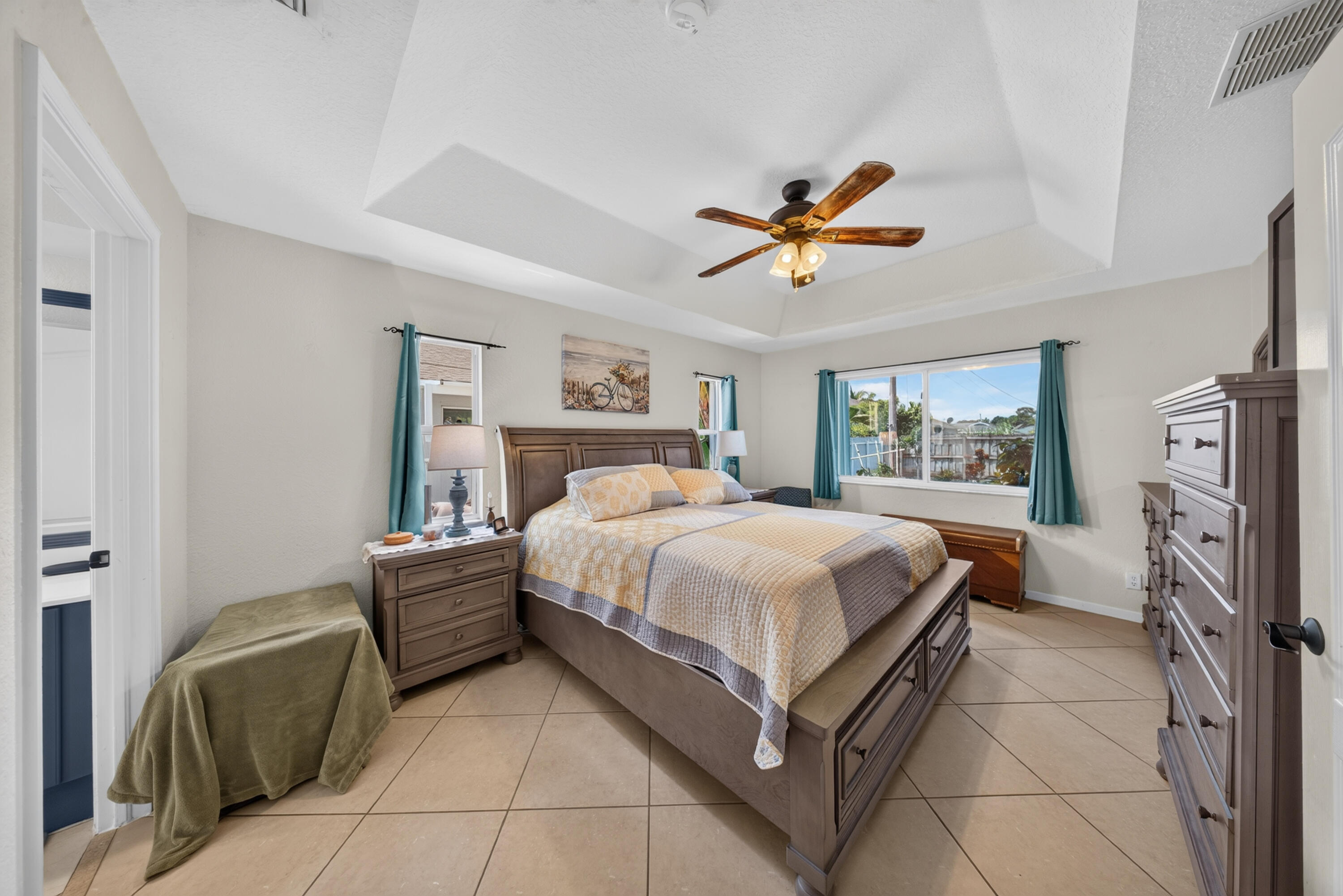 Tray ceiling with a ceiling fan, recessed lighting, tile flooring, and large windows