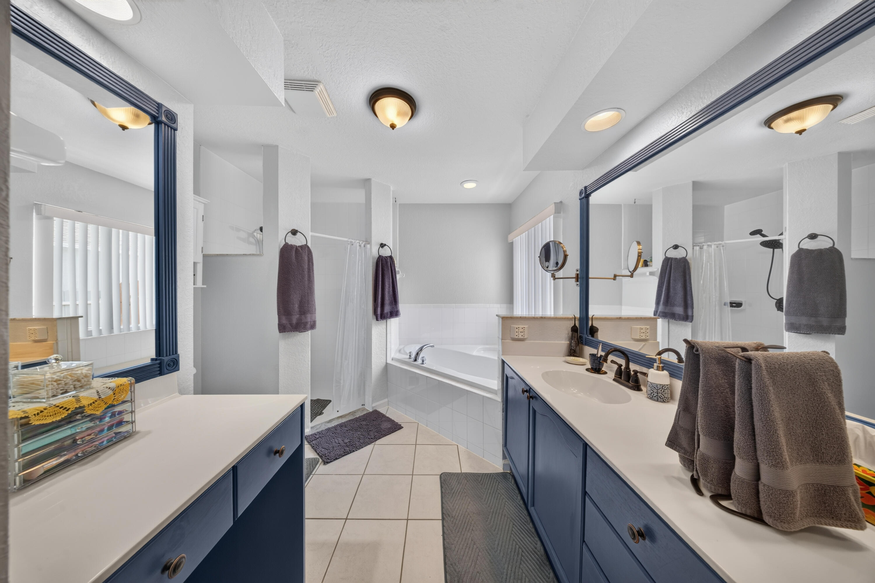 Dual vanities with integrated sinks, a built-in bathtub, a walk-in shower, and tile flooring