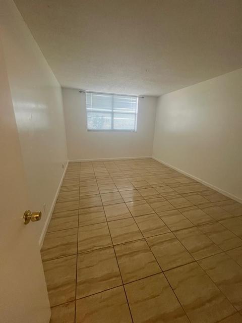 Light-toned ceramic tile flooring, neutral wall tones, and a window with horizontal blinds