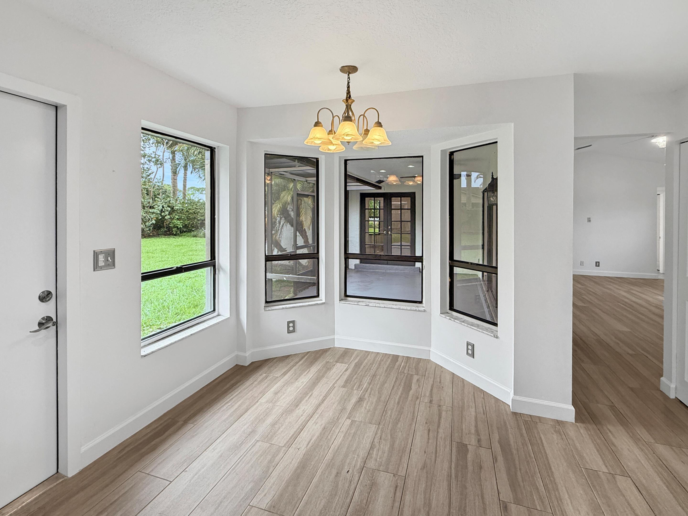 Bay window with ample natural light, wood-finish tileflooring, and a decorative chandelier