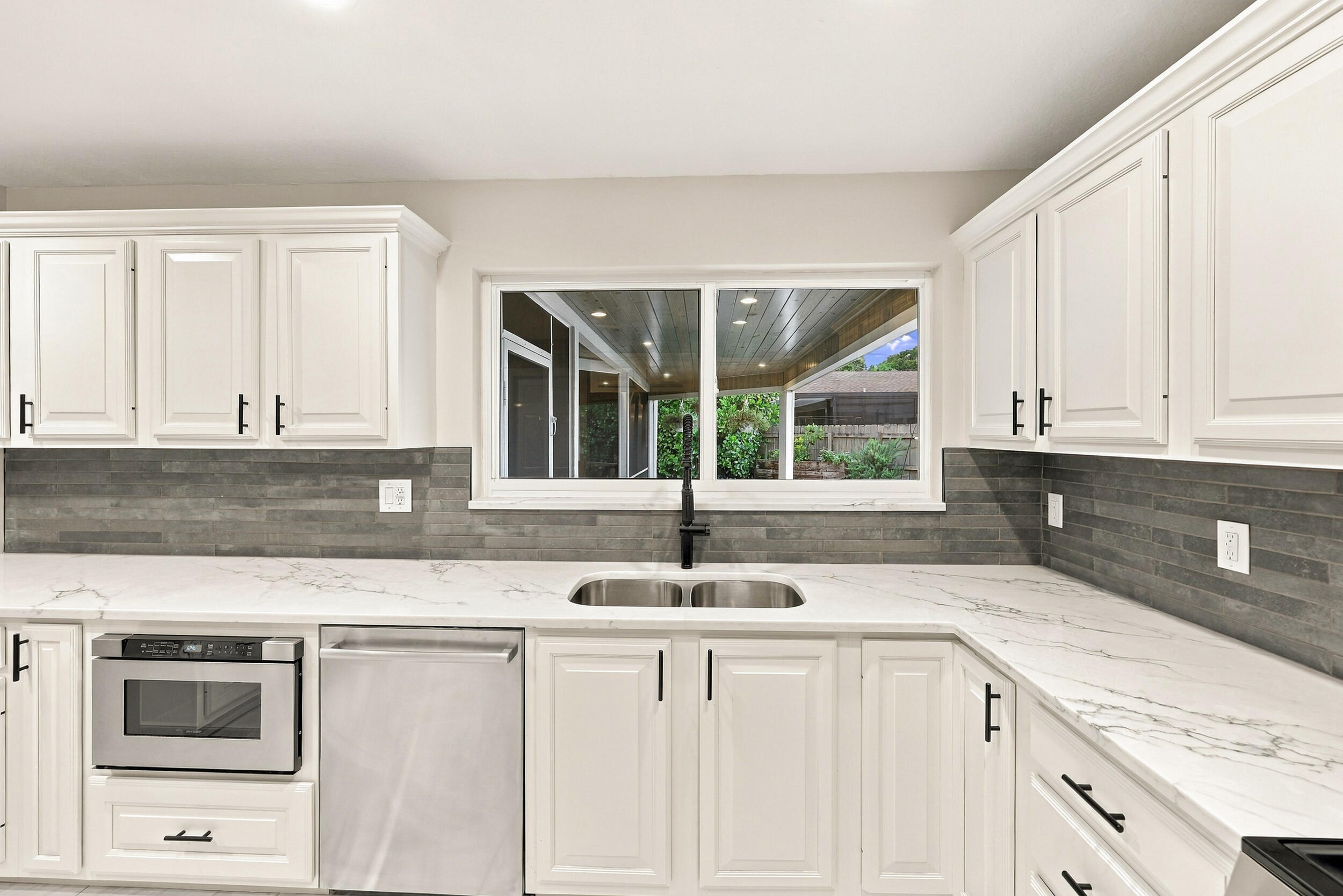 From the kitchen sink, you can admire the resort-style pool, spacious backyard, and 900-square-foot covered and screened-in patio.