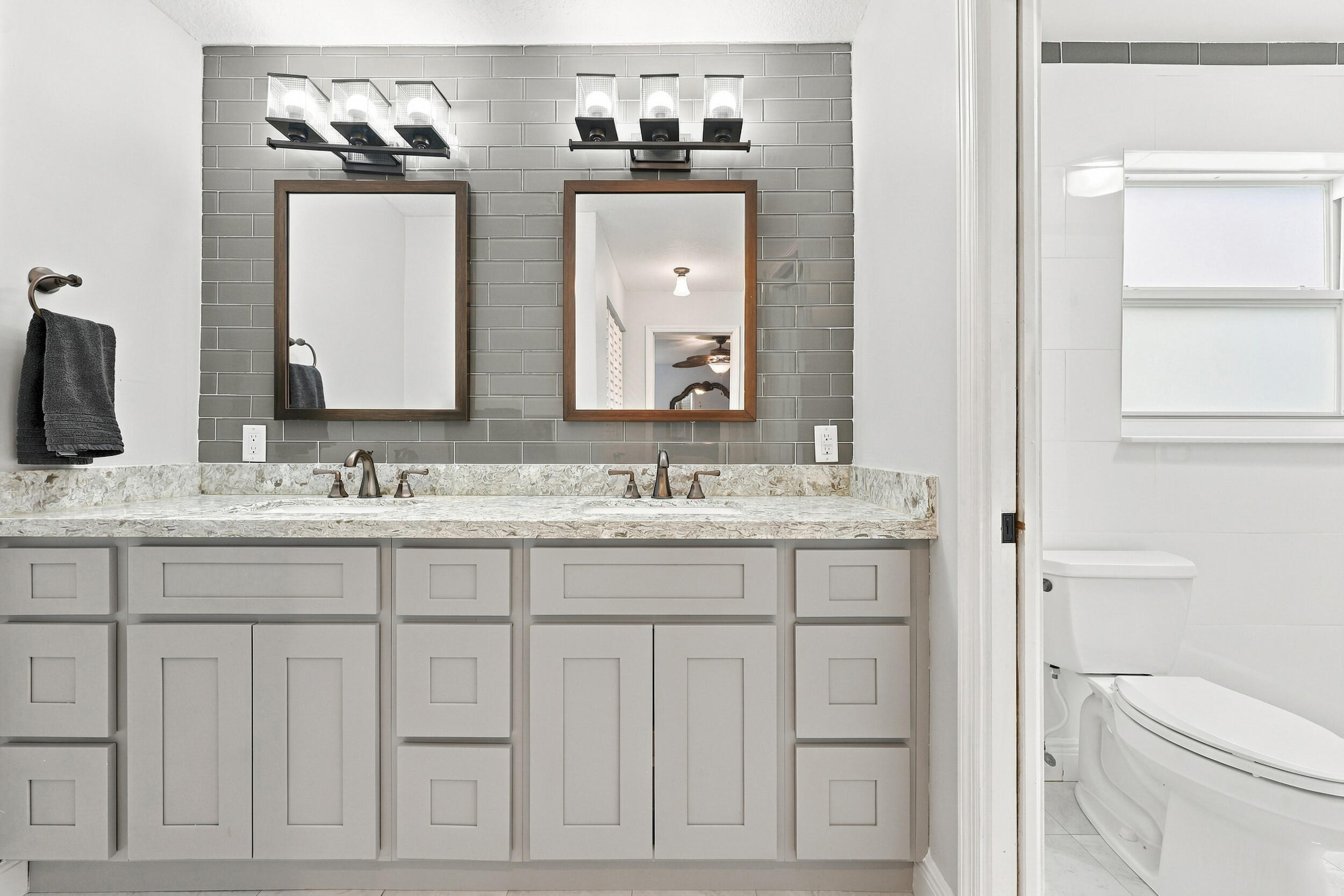 The fully renovated primary bathroom offers dual sinks, updated cabinetry, and a brand-new frameless glass shower.