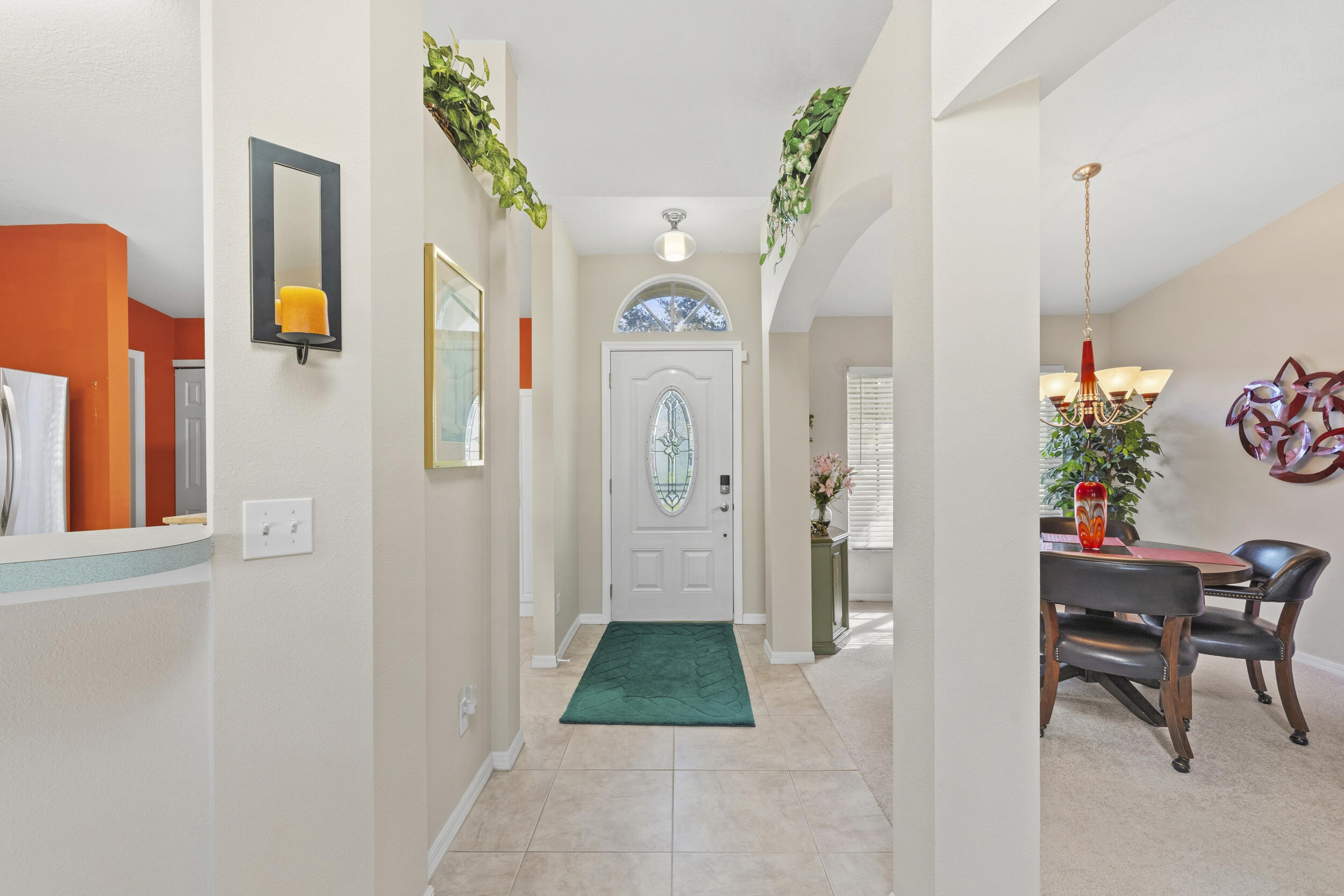 Entryway featuring ceramic tile flooring, arched wall cutouts, a six-panel front door with an oval glass insert, and a transom window