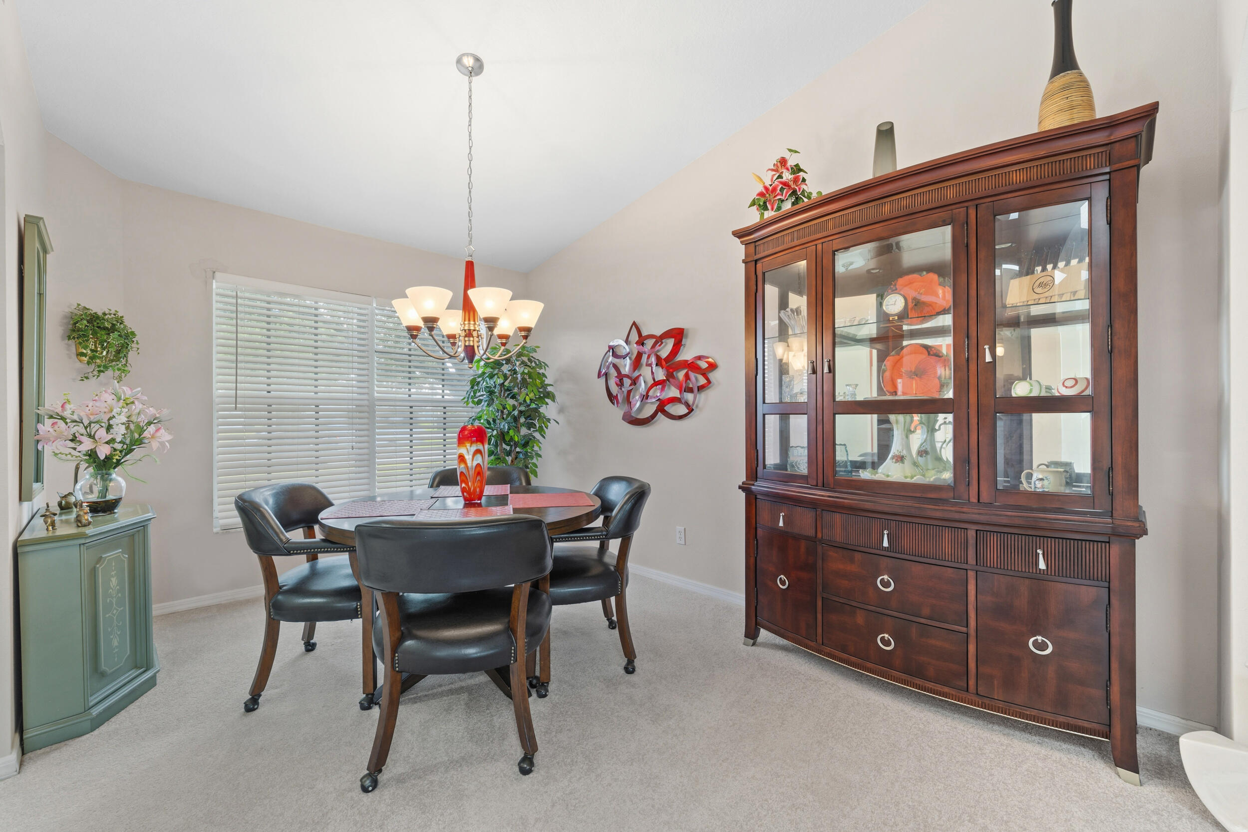 Vaulted ceiling, multi-light hanging chandelier, and horizontal blind window treatments