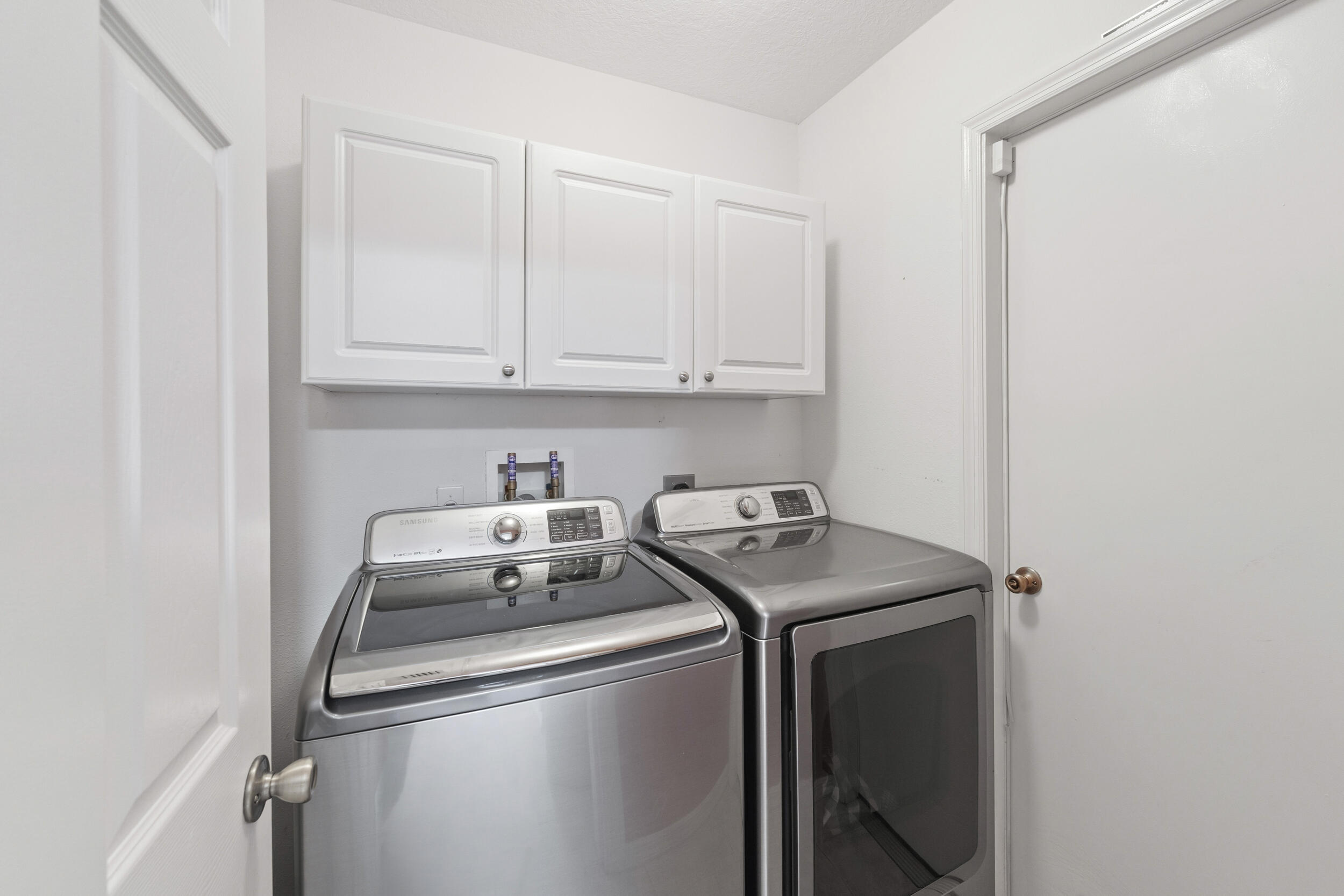 Laundry area featuring crisp white shaker-style cabinetry and dedicated washer and dryer hookups