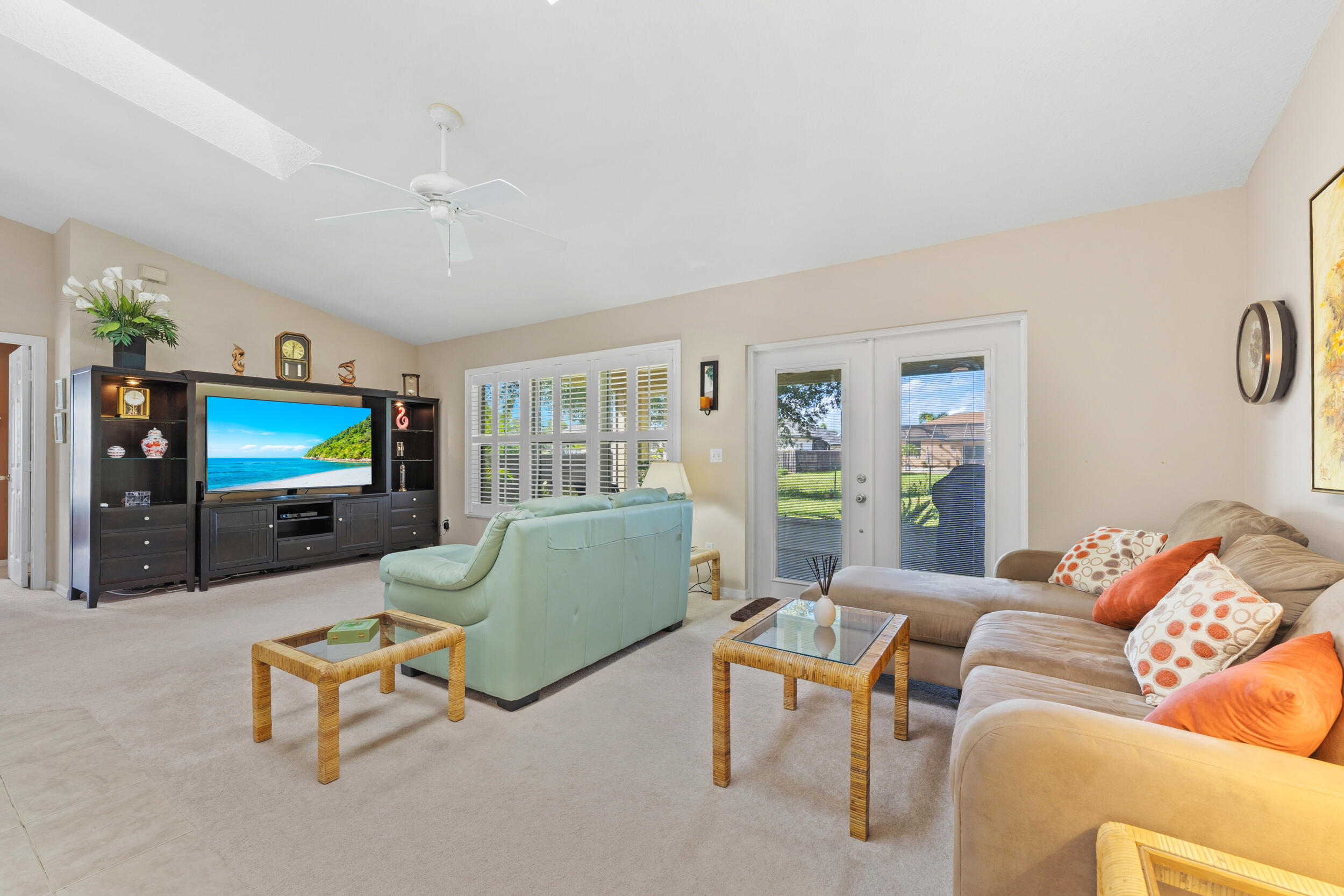 Vaulted ceiling with integrated ceiling fan, built-in cabinetry, dual-pane windows with plantation shutters, and glass-paneled french doors