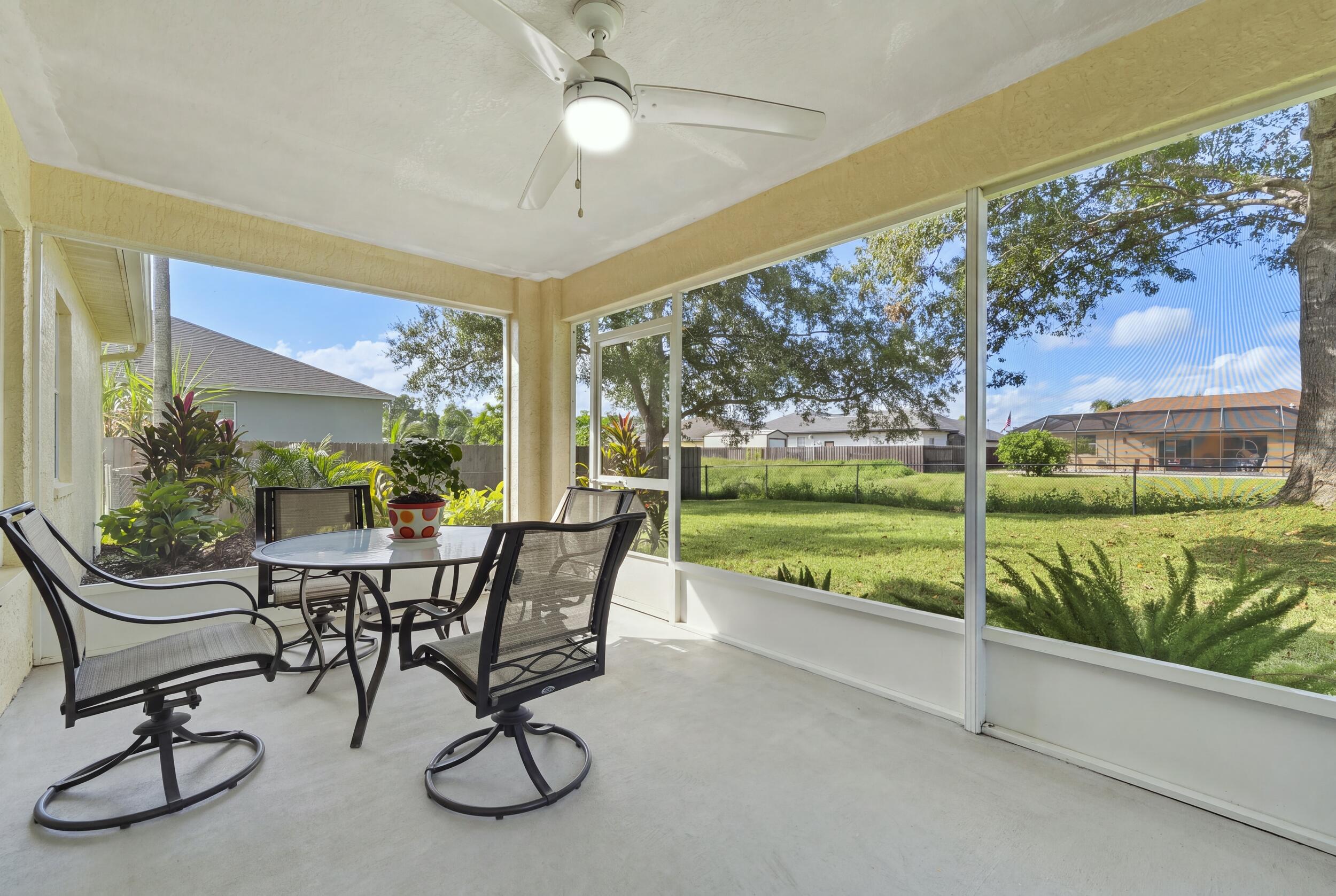 Screened-in porch featuring a concrete floor, ceiling fan with integrated lighting, and expansive mesh enclosures