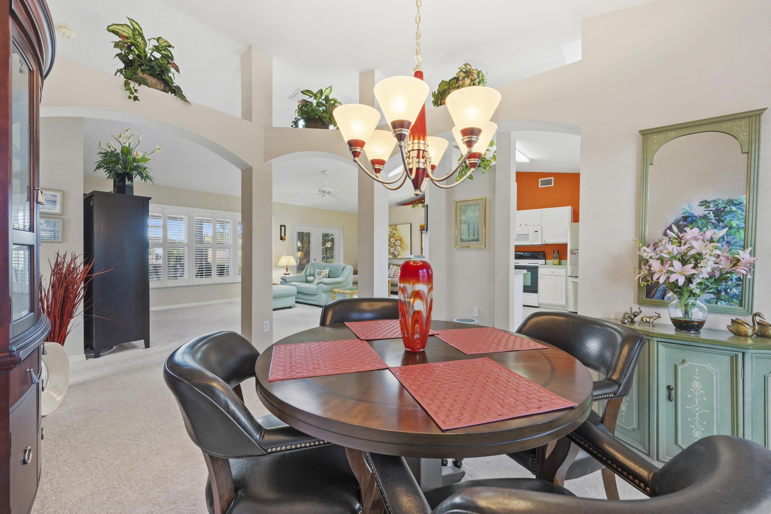 Dining area featuring arched entryways, vaulted ceilings, integrated plant ledges, and a multi-arm pendant light fixture