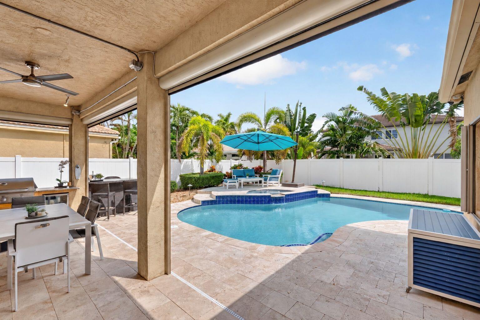 Covered patio with motorized sunshades, summer BBQ kitchen and travertine deck.