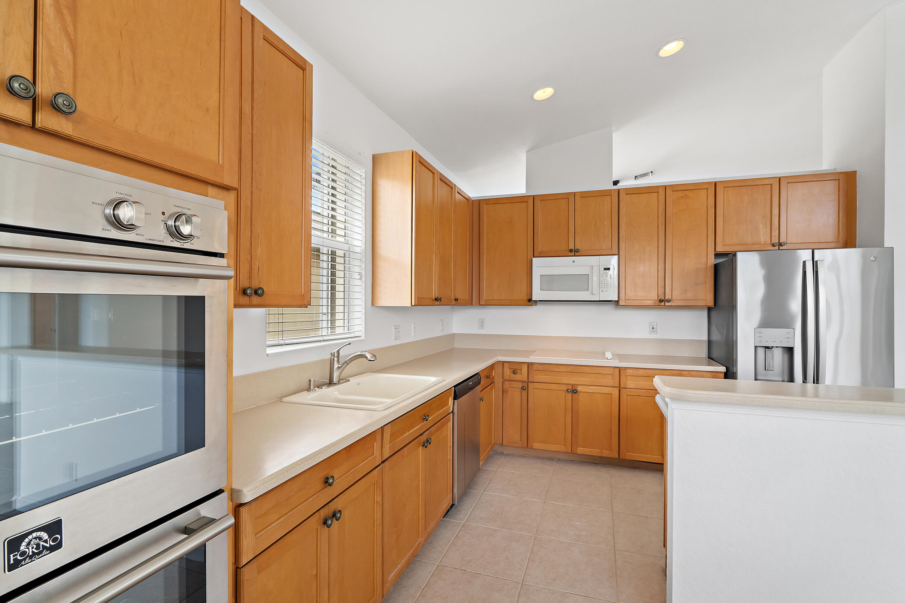 A brand-new Forno Vomero stainless double wall oven, with convection on top and traditional below, takes center stage. Wood cabinetry wraps the kitchen, a window over the sink brings in natural light, and stainless appliances complete the space. Its still under warranty and ready for your first holiday meal.