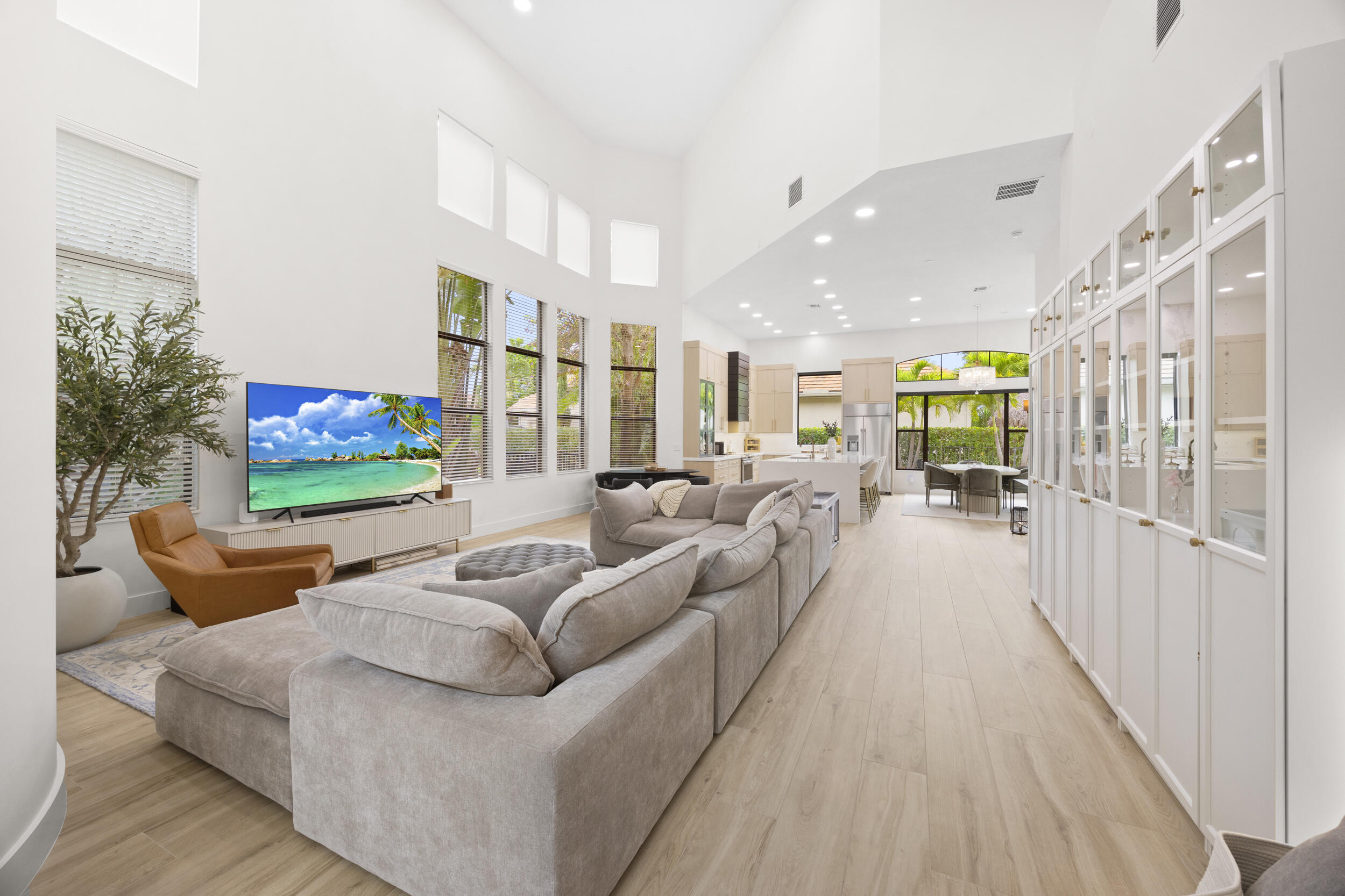 Vaulted ceilings, expansive windows, light-toned wood-finish flooring, and built-in floor-to-ceiling glass-paneled cabinetry