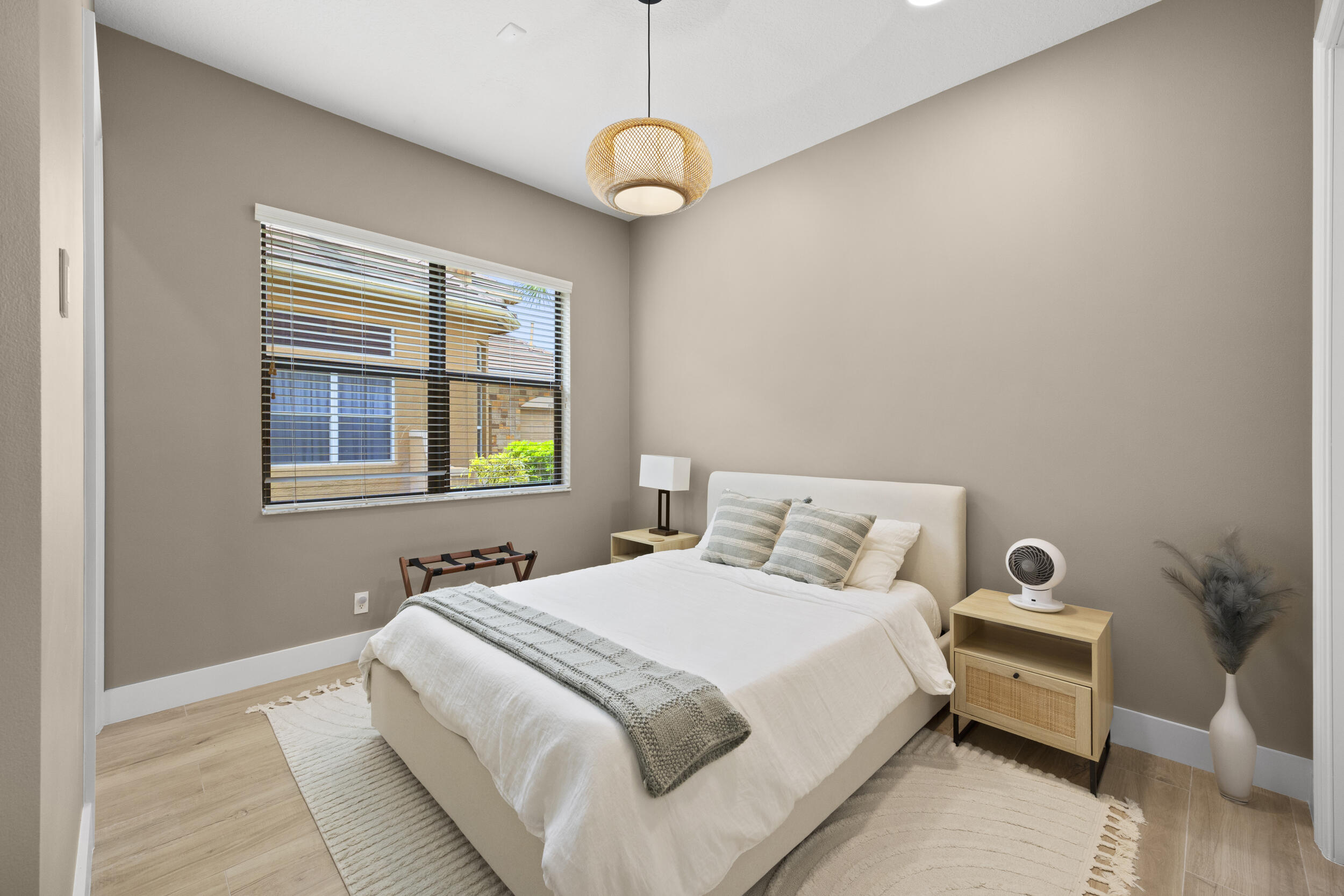 Neutral-toned interior featuring wood-finish flooring, a pendant light fixture with a textured woven shade, and a horizontal sliding window with integrated blinds