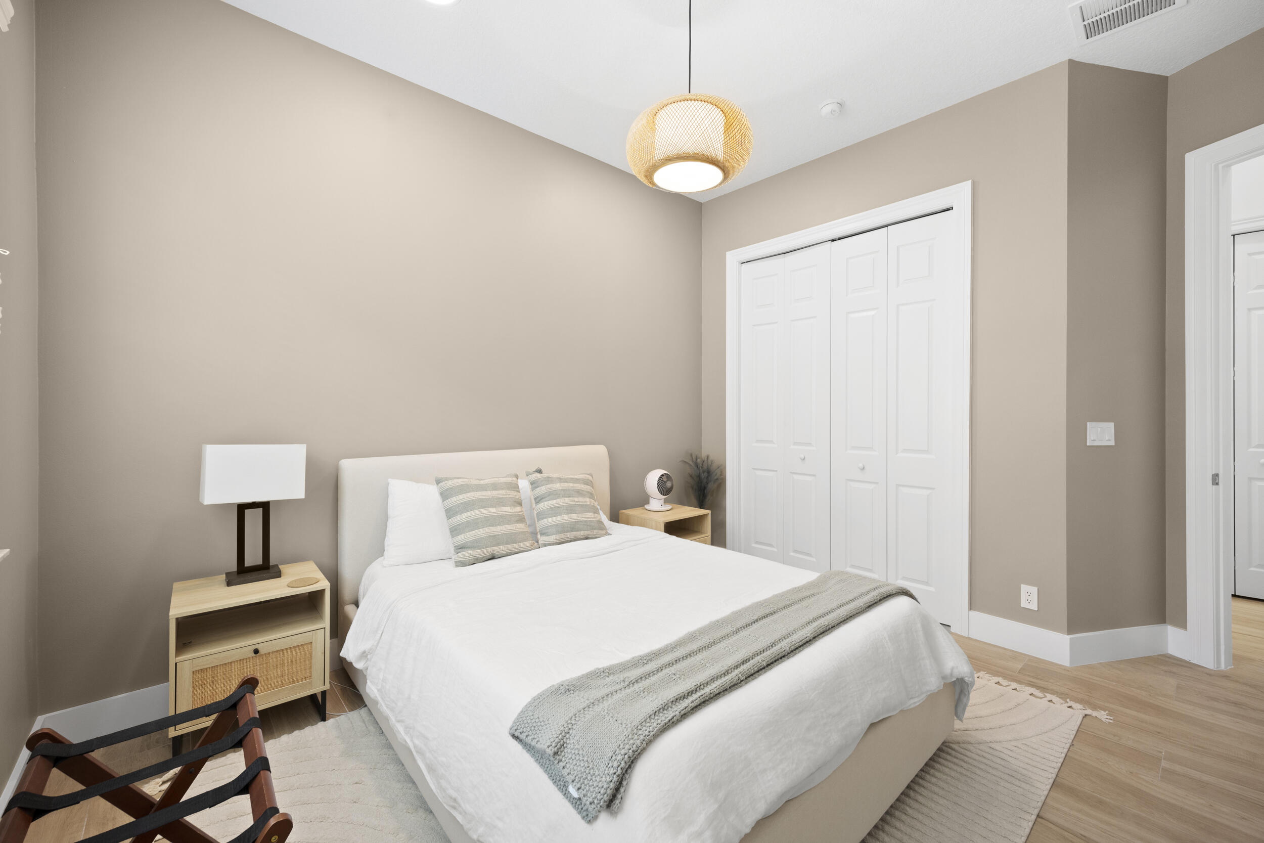 Neutral interior walls, wood-finish flooring, recessed lighting, white panel-style closet doors, and a woven pendant light fixture