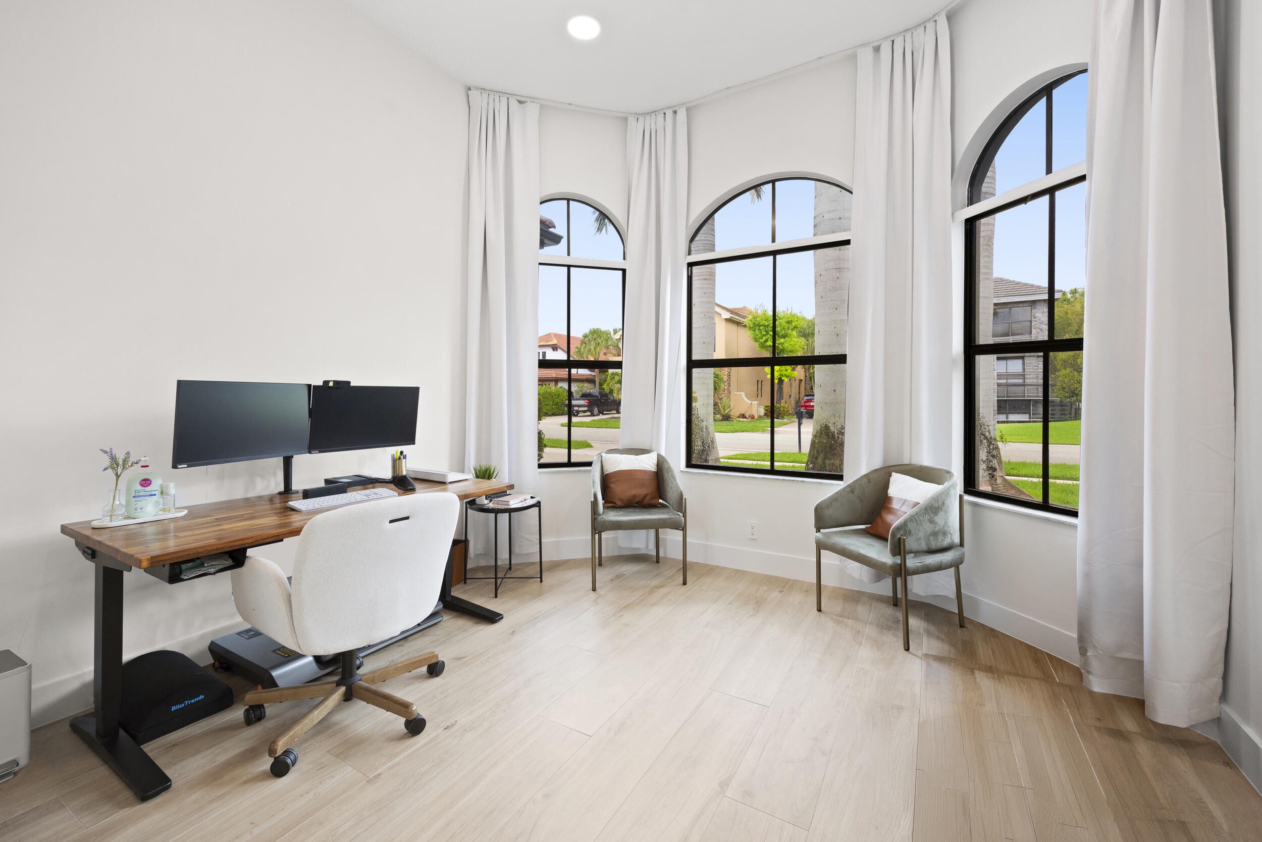 Room featuring wood-finish flooring, three arched windows with black frames, and recessed lighting