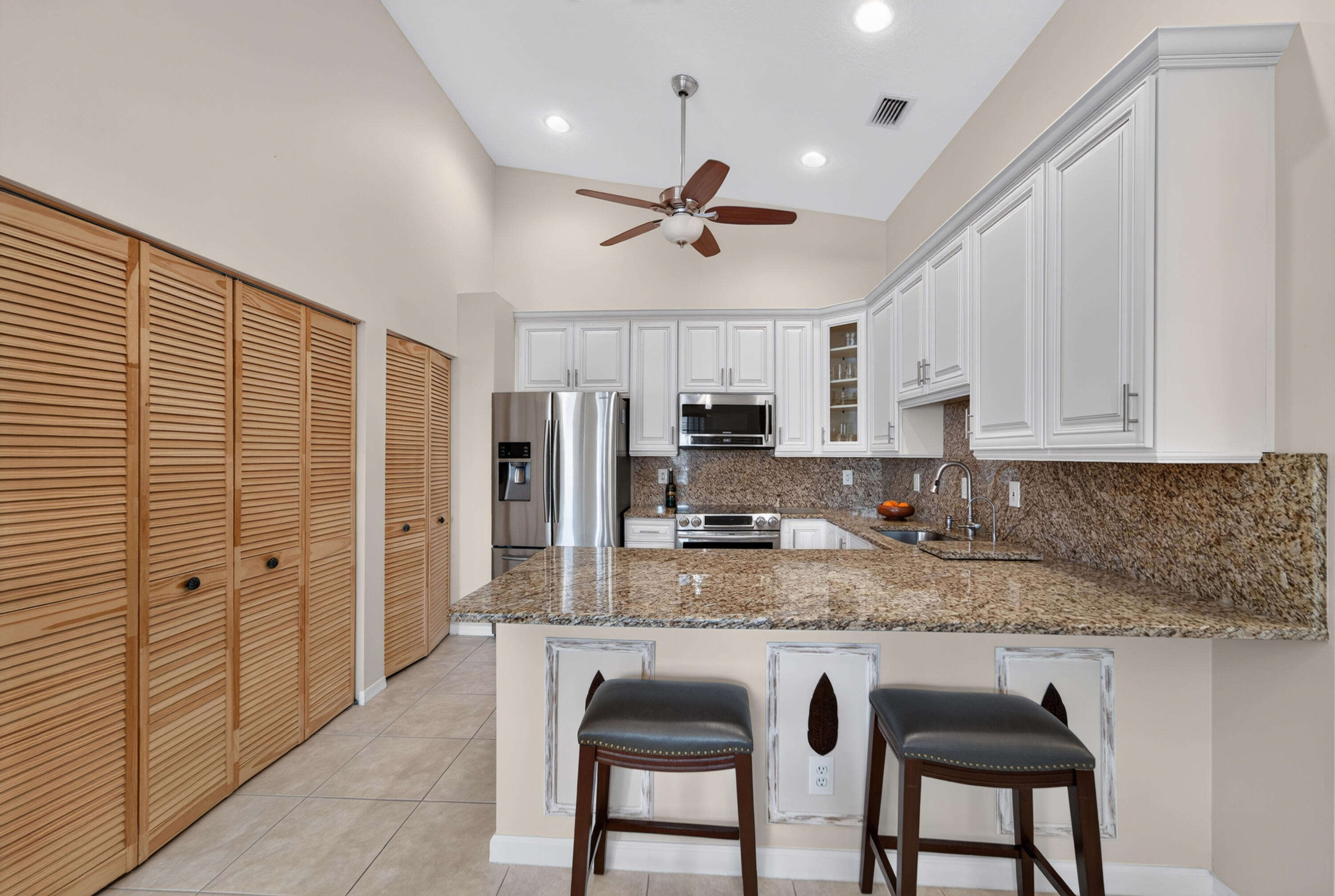 Large penisula granite island with bar stools, soft close doors, vaulted ceilings, fan, doors to washer in dryer in unit.