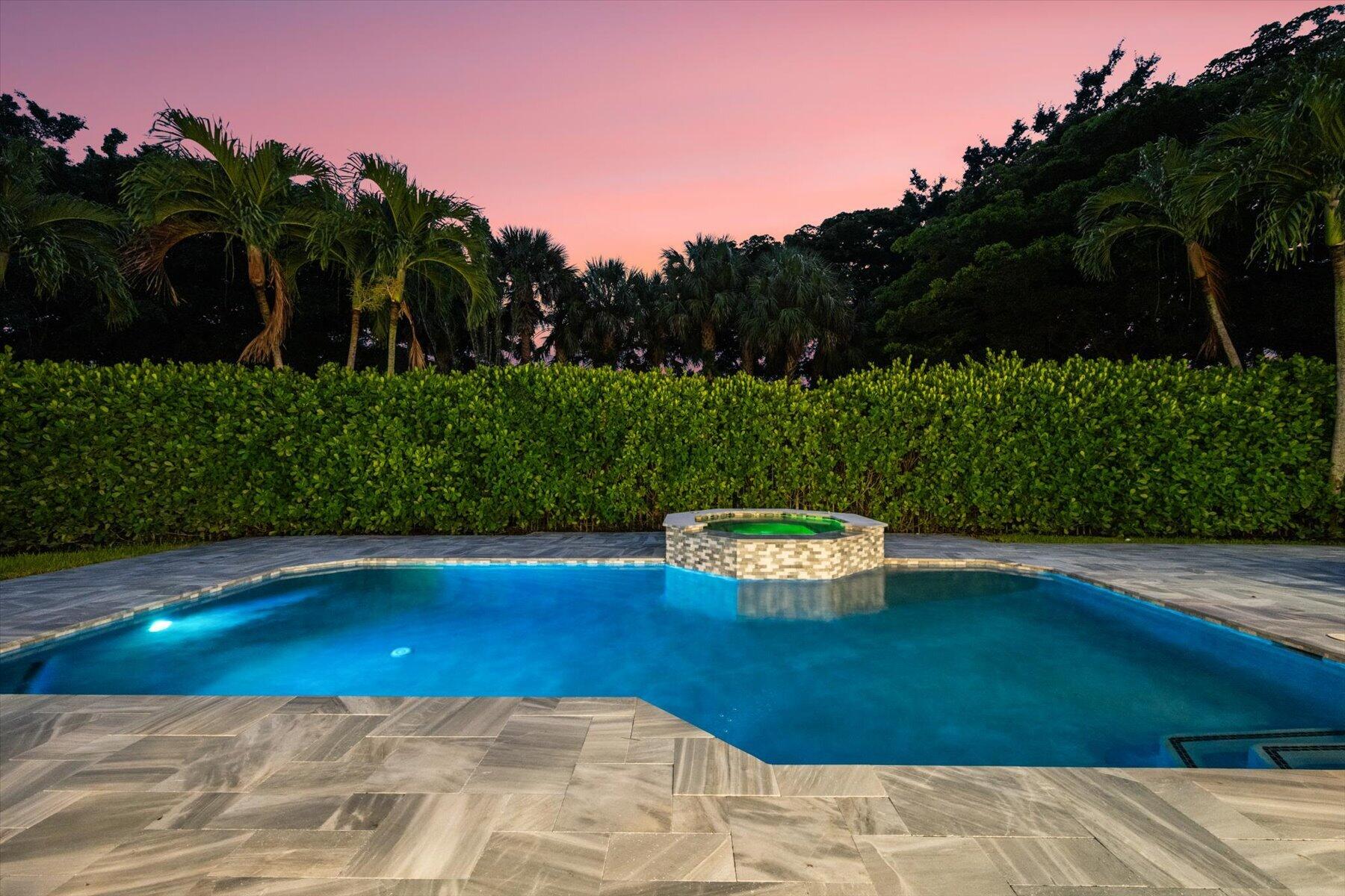 Swimming pool with a stone-accented raised spa, surrounded by natural stone pavers and mature landscaping