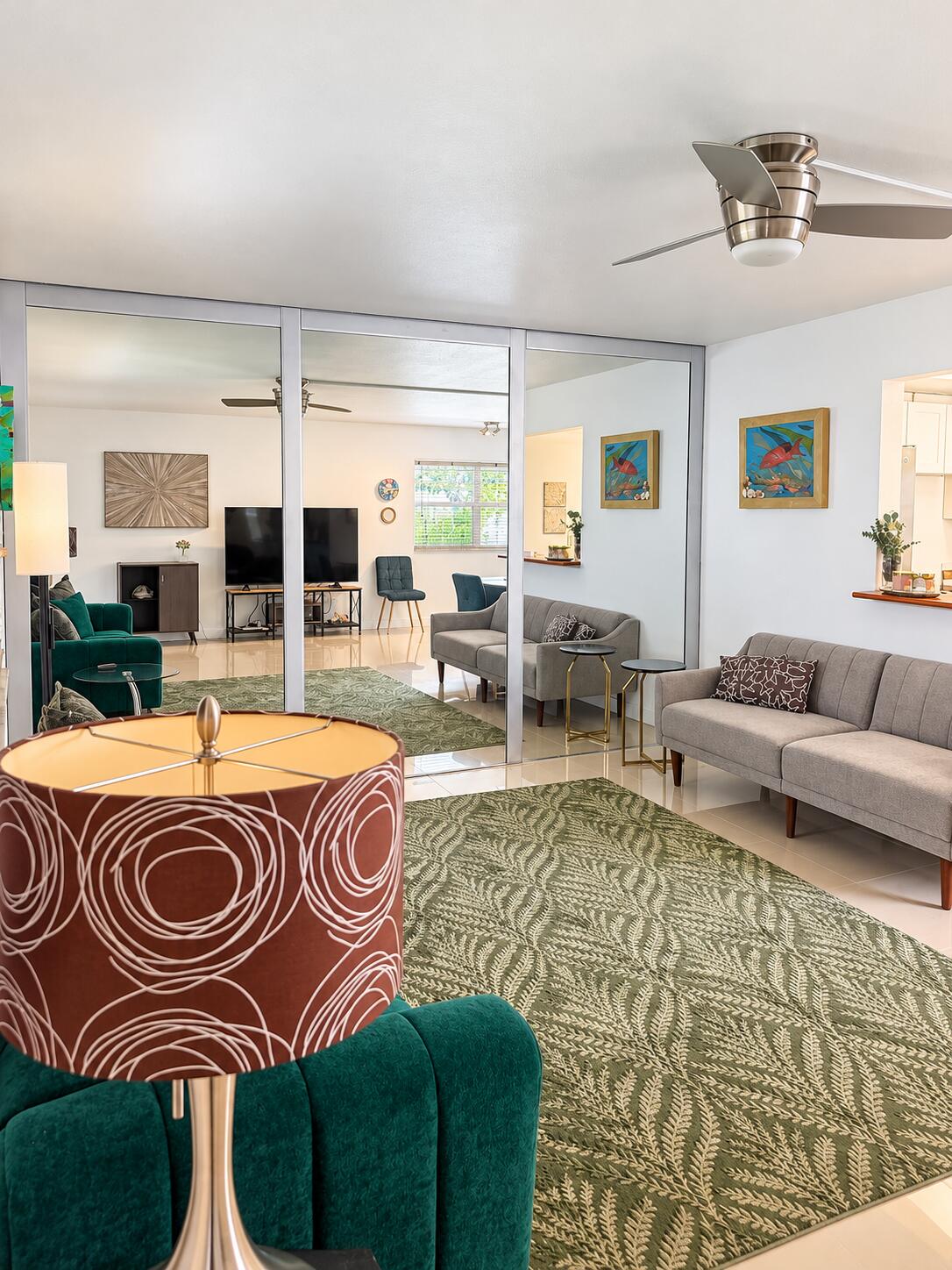 Floor-to-ceiling mirrored wall panels, polished tile flooring, brushed-nickel ceiling fan with integrated lighting, and a pass-through window with a wood-finish ledge