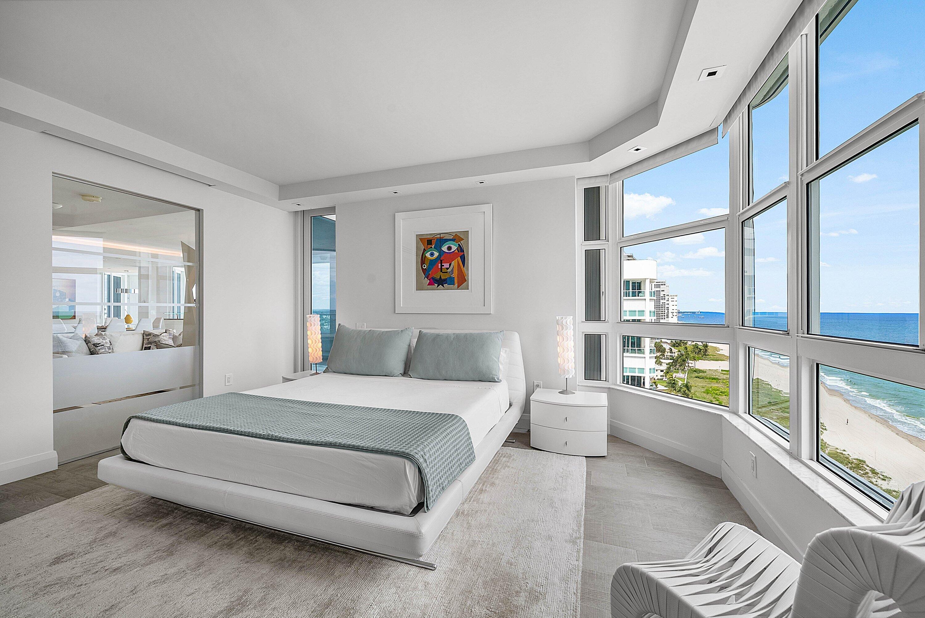 Floor-to-ceiling bay windows with oceanfront exposure, large-format tile flooring, recessed lighting, and mirrored wall panels