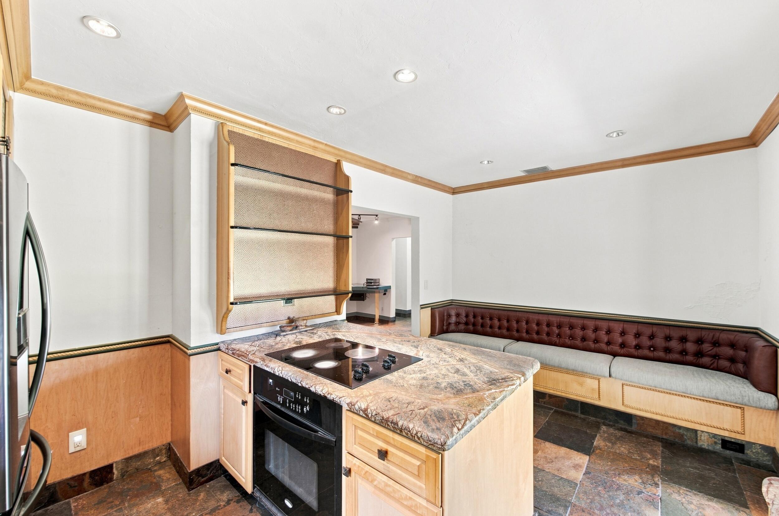 Galley kitchen featuring stainless steel appliances, wood-finish cabinetry, and patterned stone countertops