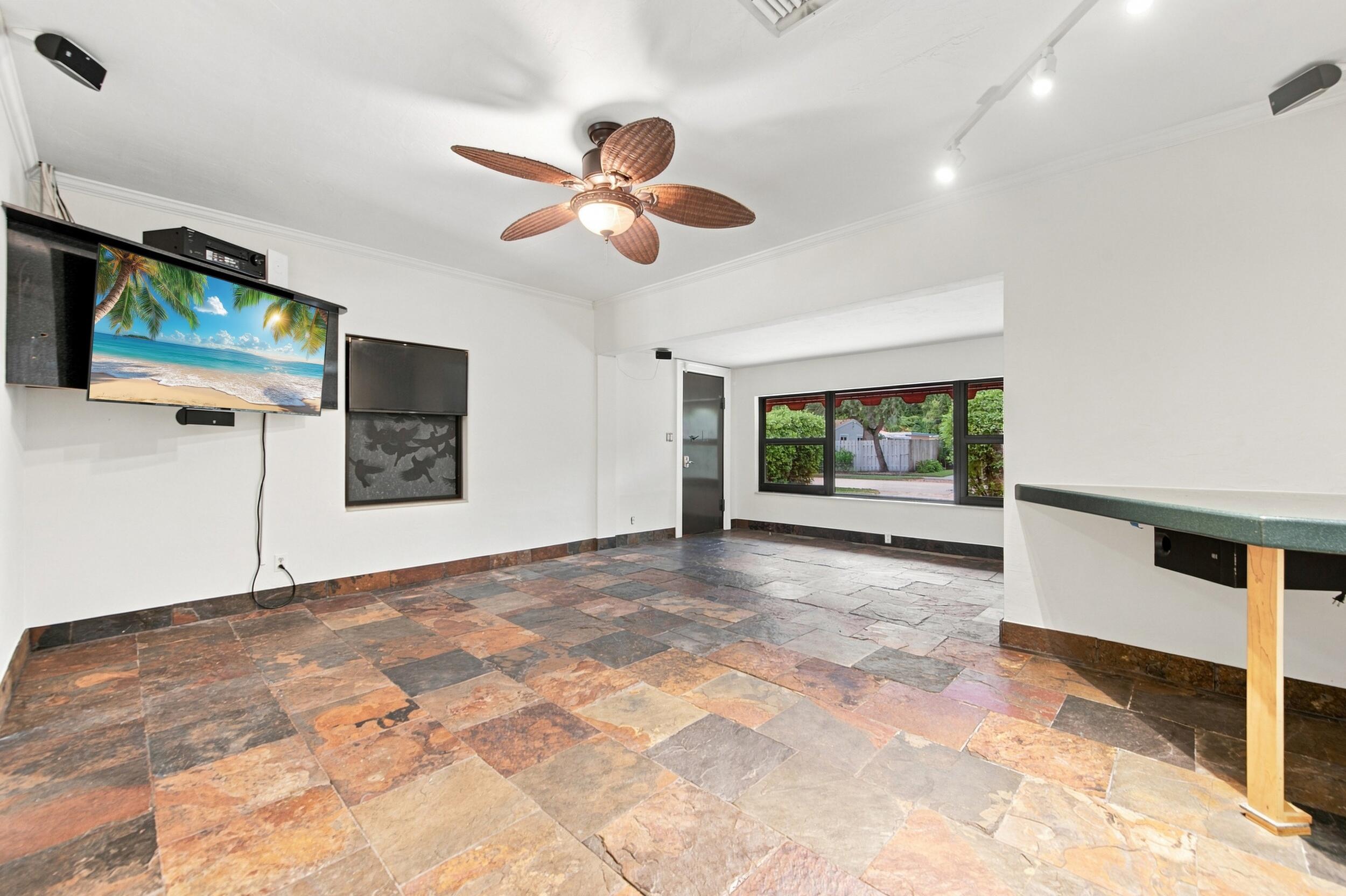 Multi-toned slate tile flooring, ceiling fan with palm-style blades, adjustable track lighting, and a built-in counter surface