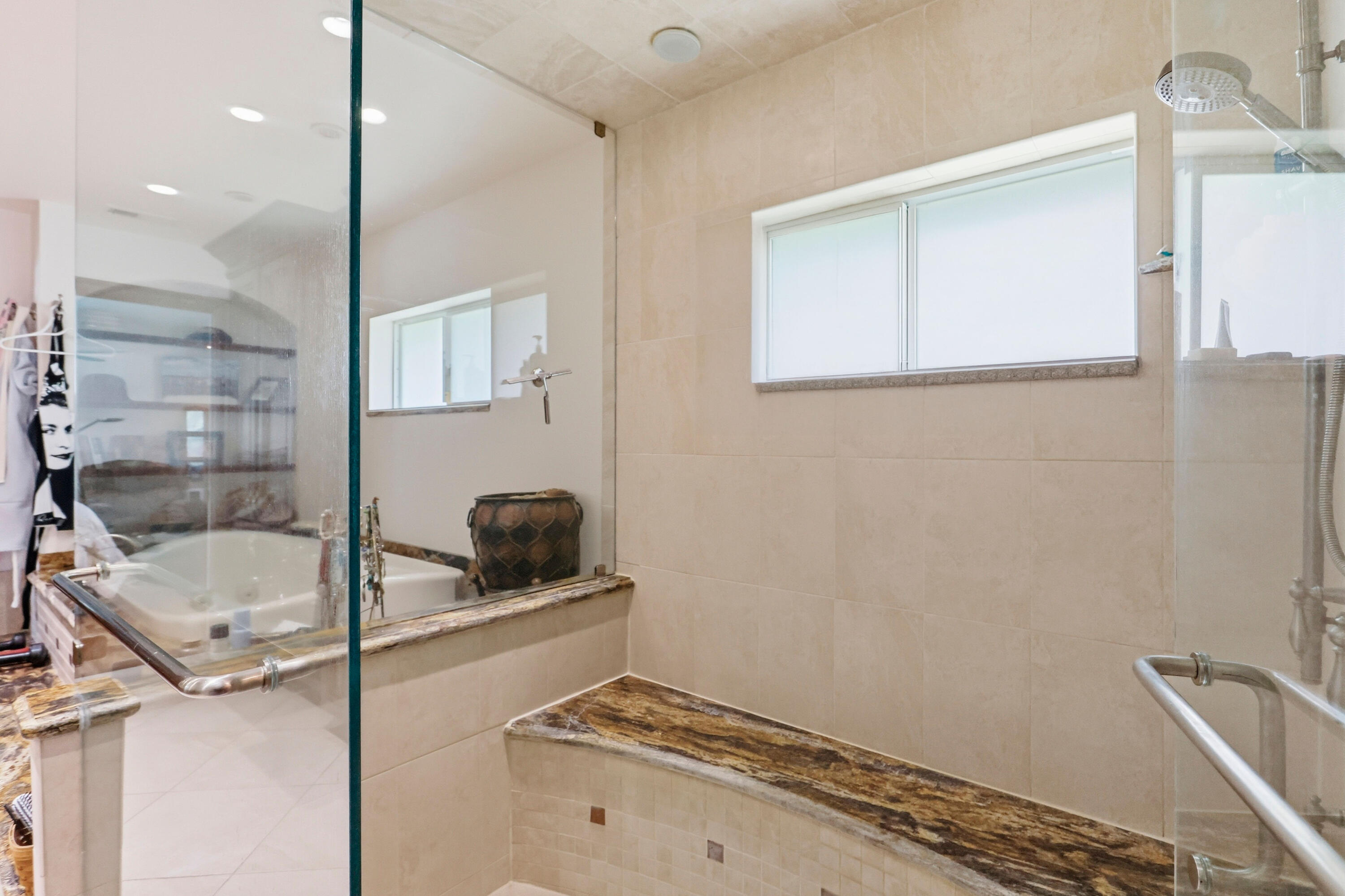 Walk-in shower featuring a glass enclosure, built-in stone bench, integrated rain shower head, and neutral large-format wall tile