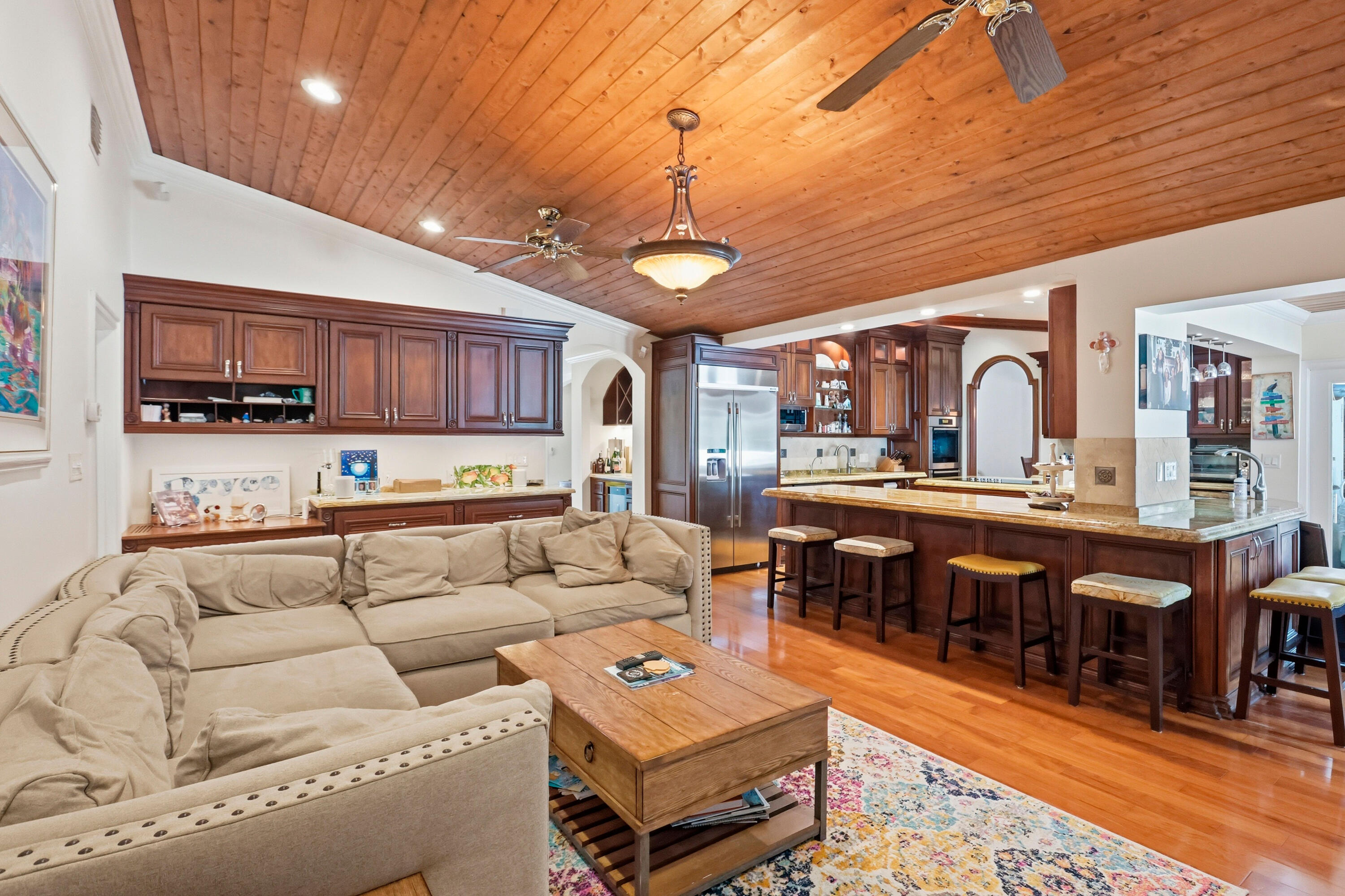 Vaulted wood-plank ceiling featuring recessed lighting, custom wood cabinetry, stone countertops, and wood-finish flooring