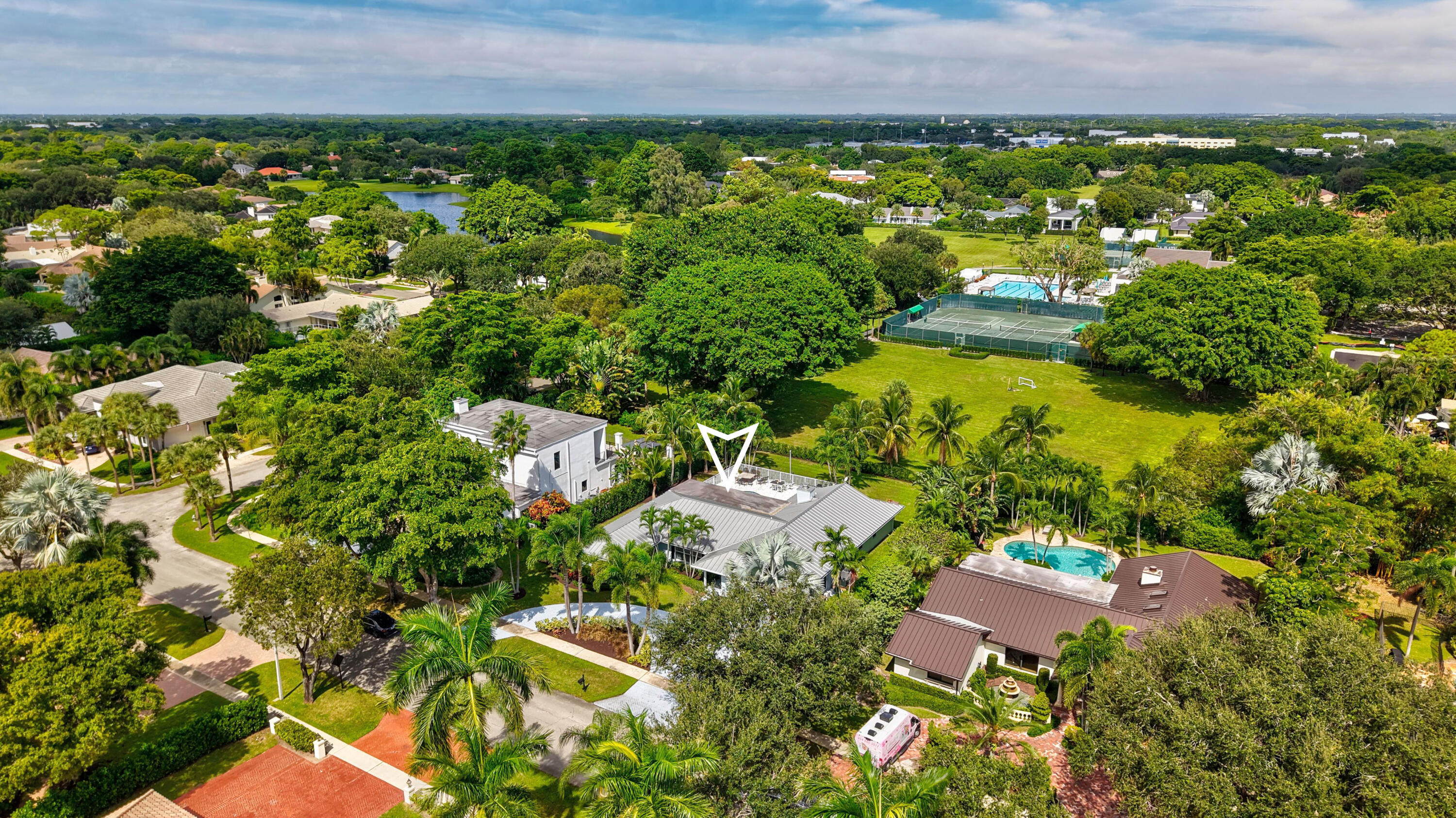 Aerial perspective featuring a residential lot with mature trees, landscaped grounds, and a private swimming pool
