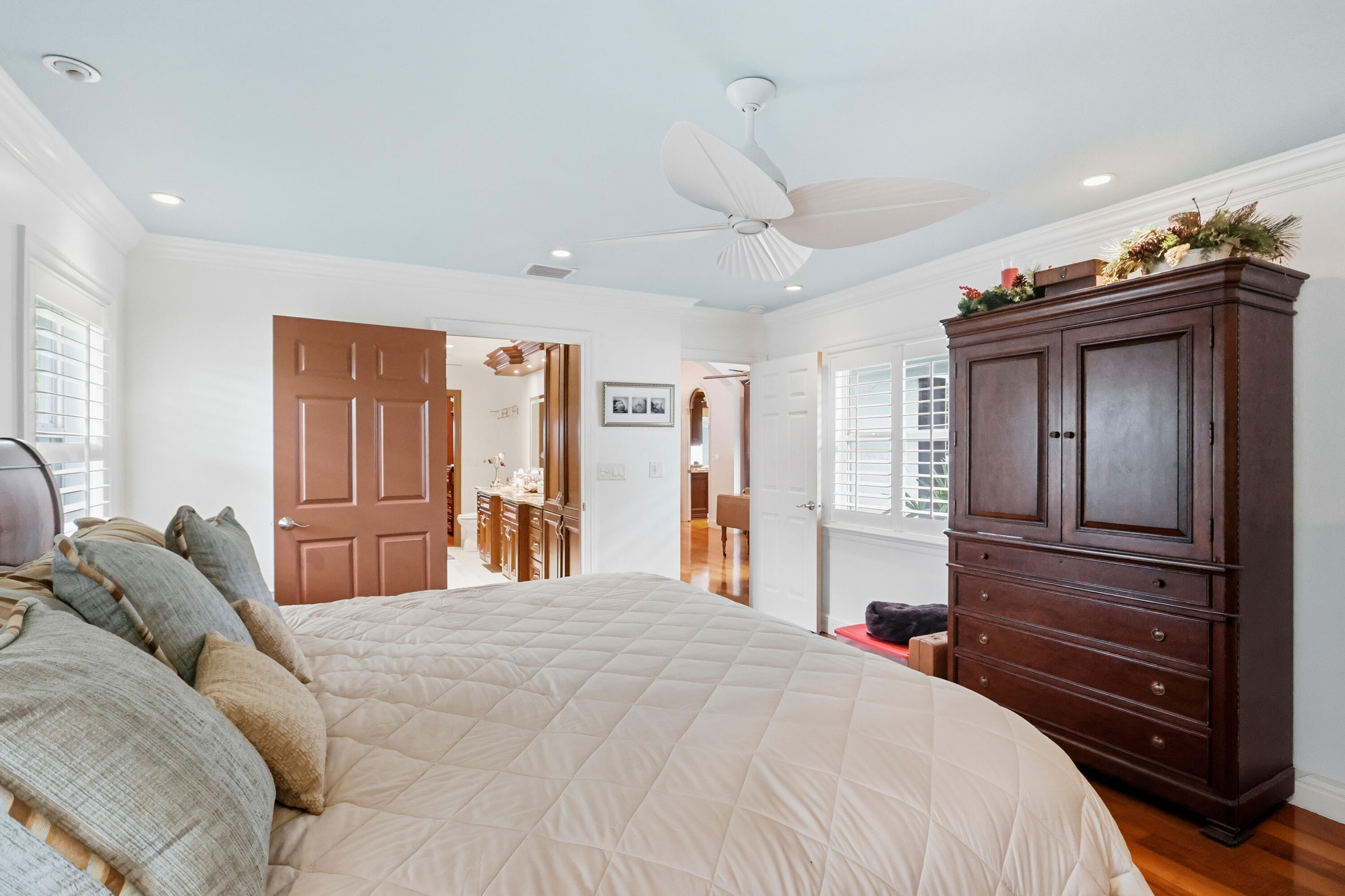 Room featuring light blue ceiling, recessed lighting, white louvered shutters, crown molding, and a three-blade ceiling fan