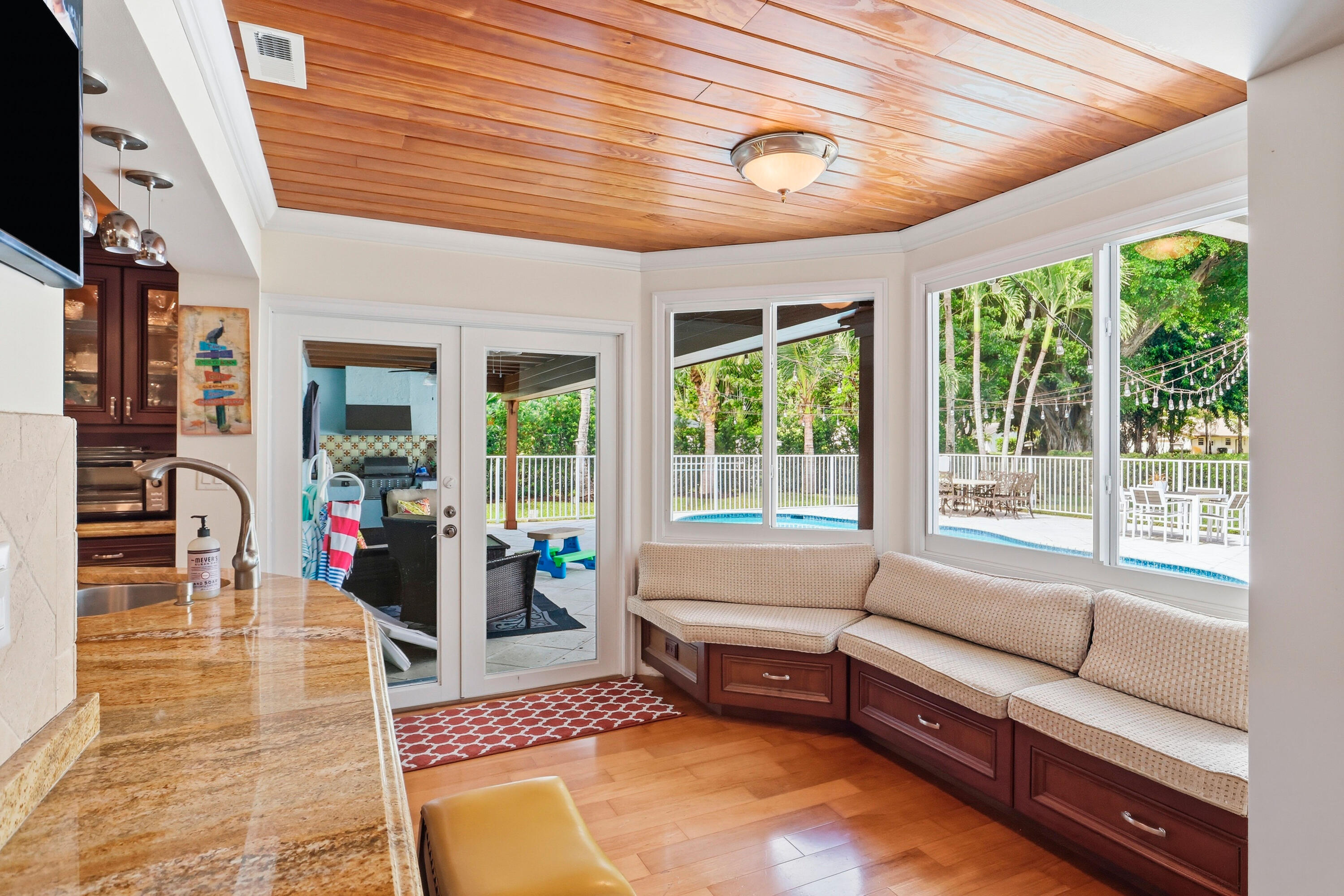 Tongue-and-groove wood ceiling, built-in bench seating with cabinetry, stone-finish countertops, wood-finish flooring, and double glass-paneled doors
