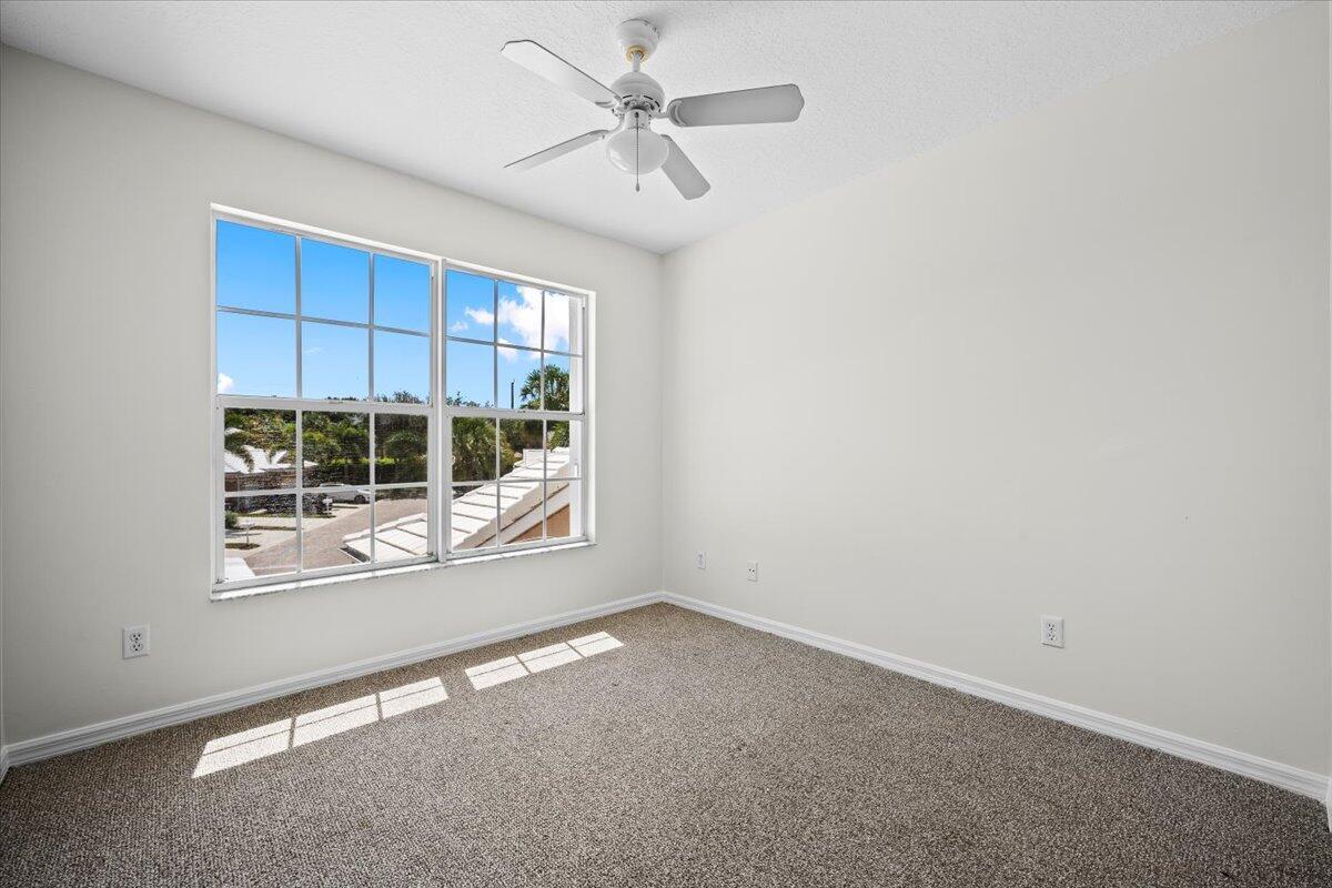 Comfortable bedroom featuring carpeting, ceiling fan, and a large window.