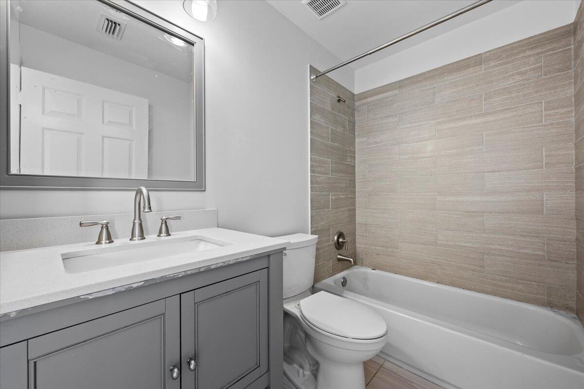 Full bathroom with double-sink vanity, tub and shower combination, and tile finishes.