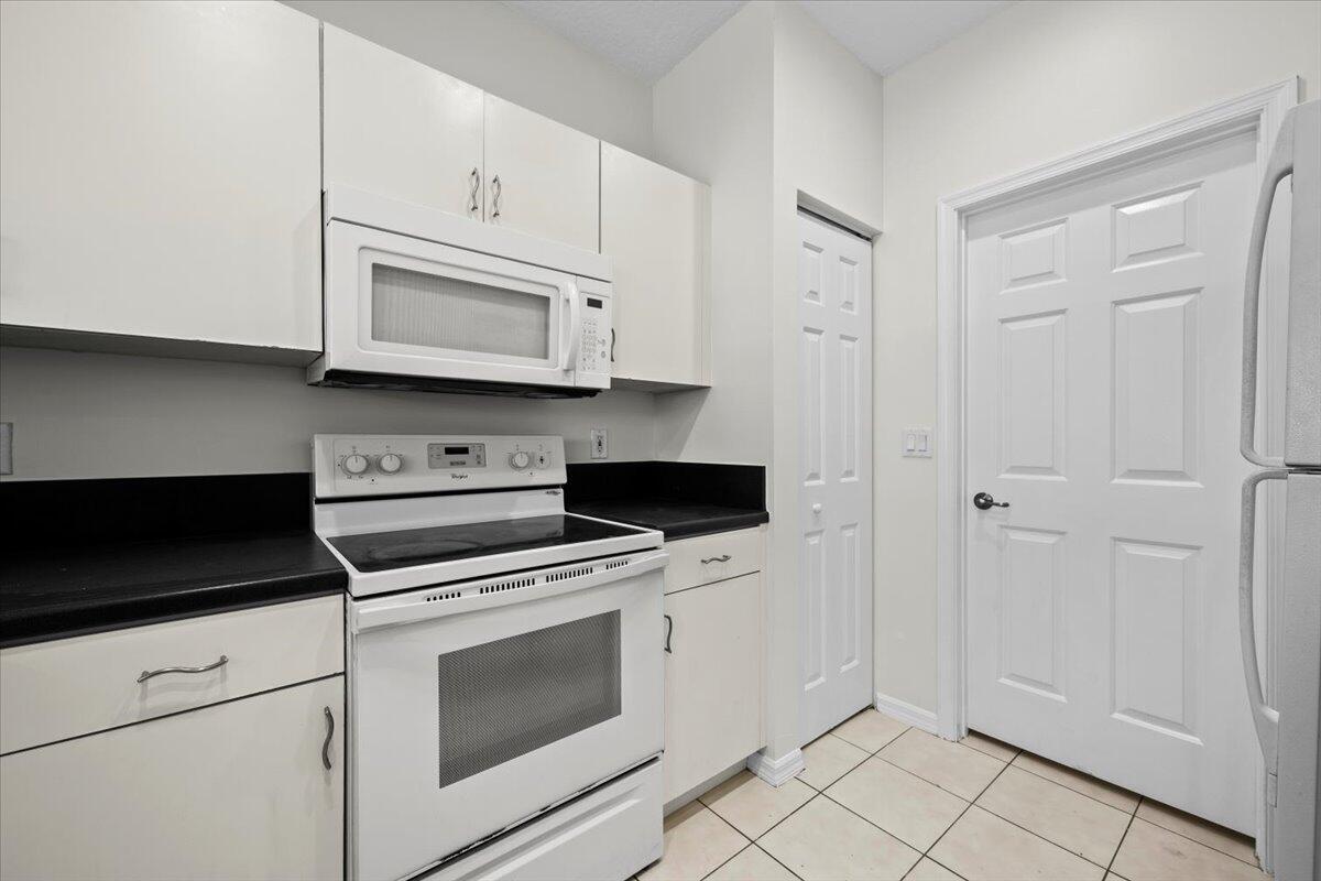 Kitchen featuring white appliances, ample cabinetry, and tile flooring. Kitchen featuring white appliances, ample cabinetry, and tile flooring.
