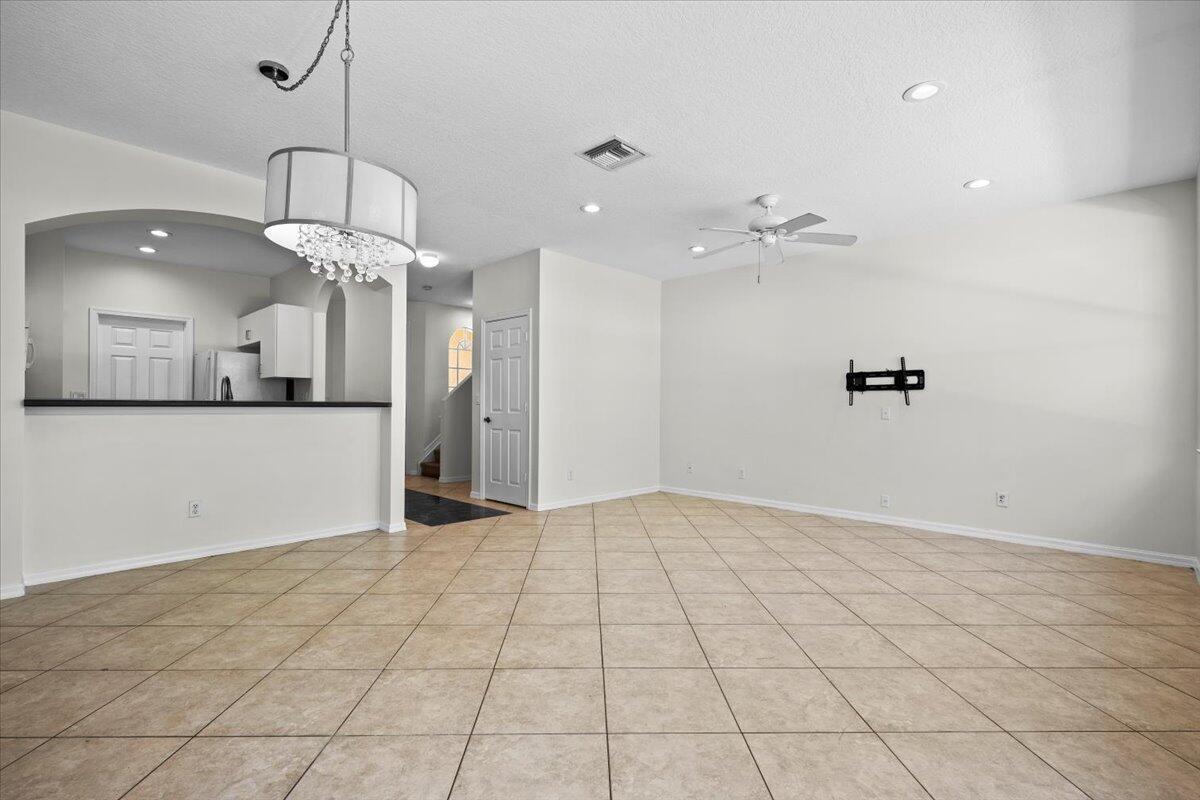 Another view of the versatile living and dining space with a modern light fixture and neutral finishes.