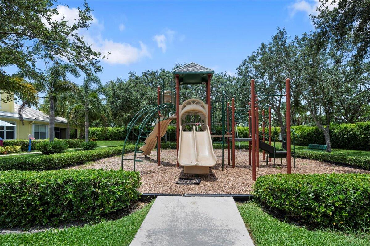 Neighborhood playground surrounded by tropical landscaping and green space.