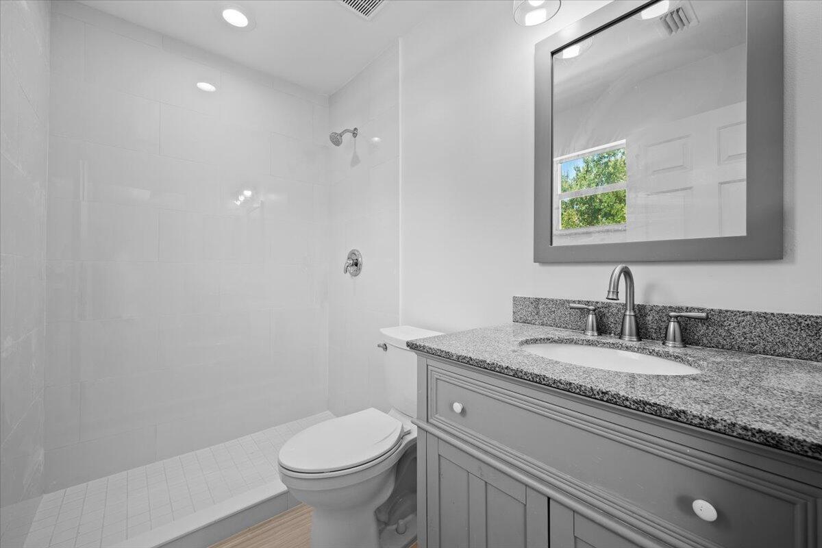 Private bathroom featuring a spacious vanity with granite countertop, walk-in shower, and neutral finishes.