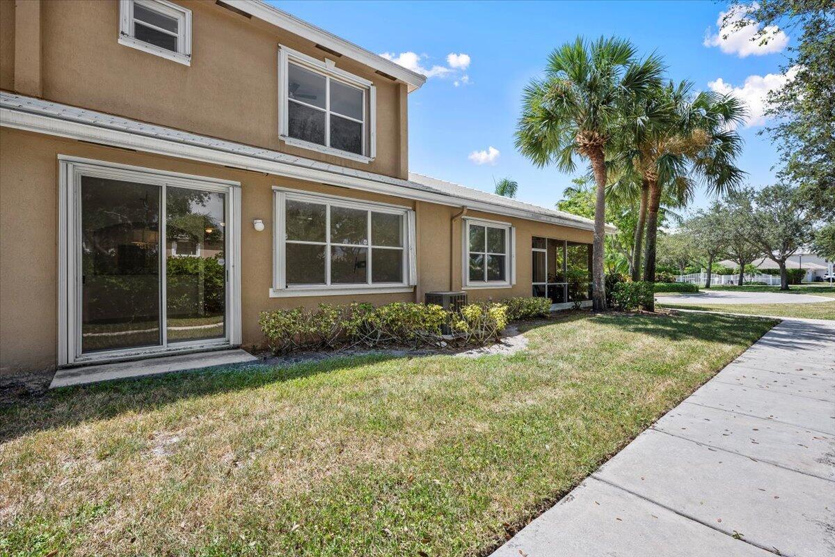 Rear view of the townhome with sliding glass doors, large windows, and a backyard area. Rear view of the townhome with sliding glass doors, large windows, and a backyard area.