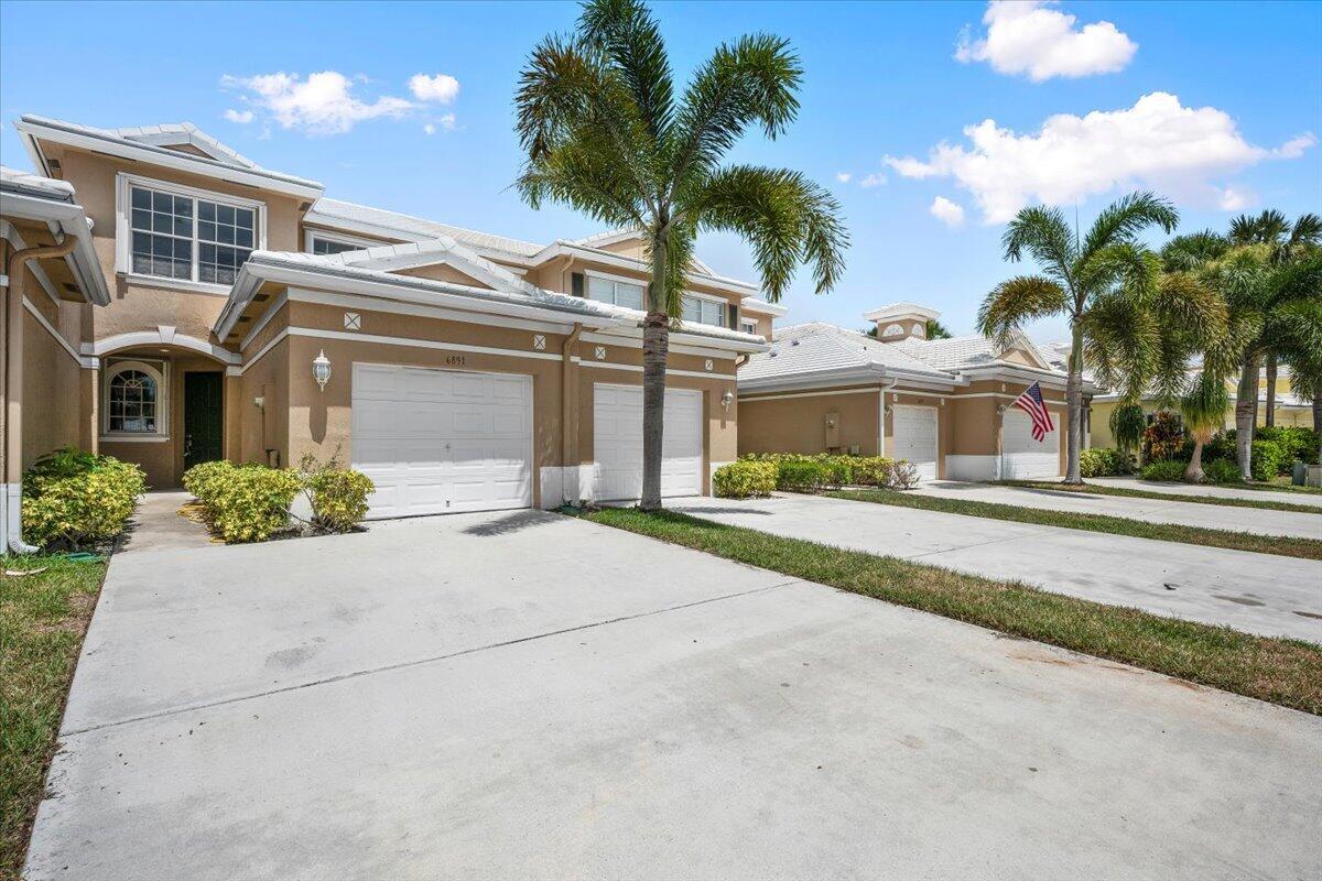 dditional view of the home featuring palm trees, landscaping, and a spacious driveway. dditional view of the home featuring palm trees, landscaping, and a spacious driveway.