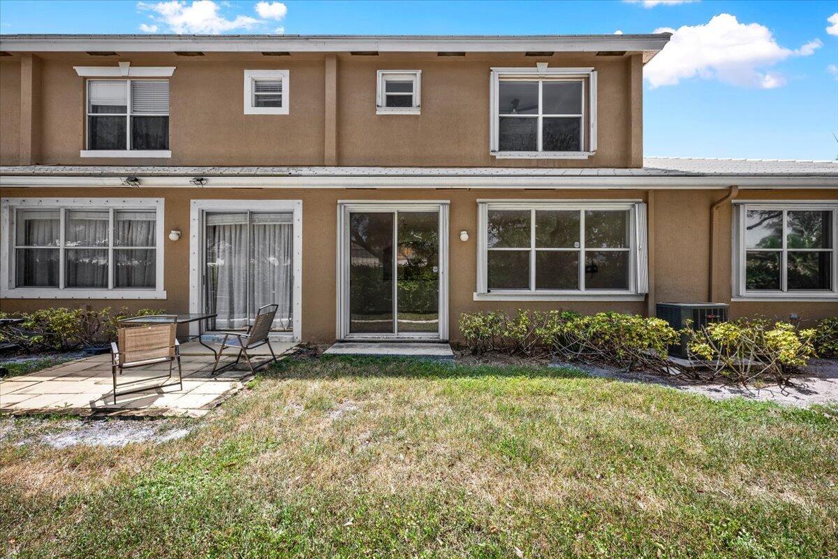Rear view of the townhome with sliding glass doors, large windows, and a backyard area. Rear view of the townhome with sliding glass doors, large windows, and a backyard area.