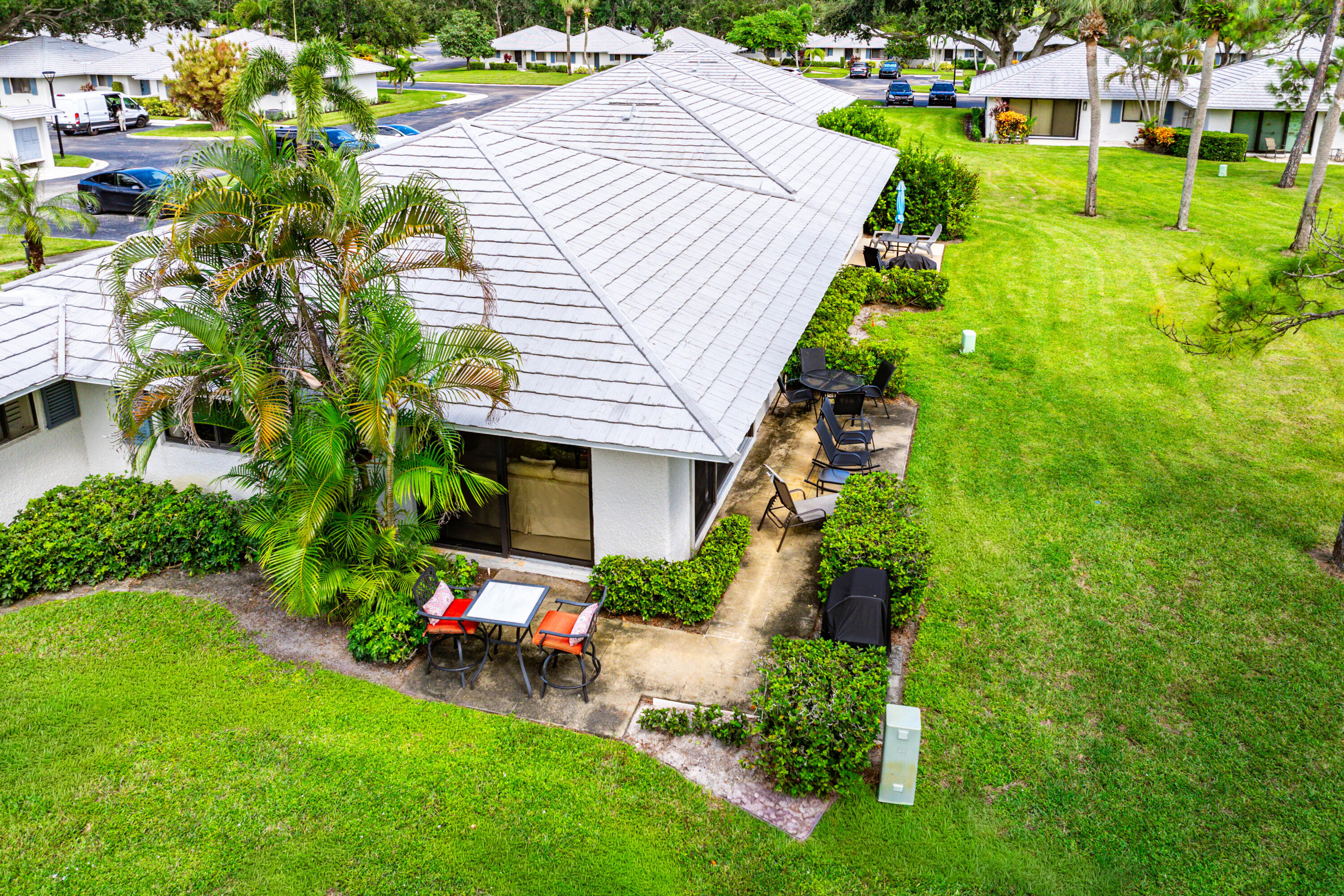 Single-story residence featuring a tile roof, concrete patio, and mature landscaping