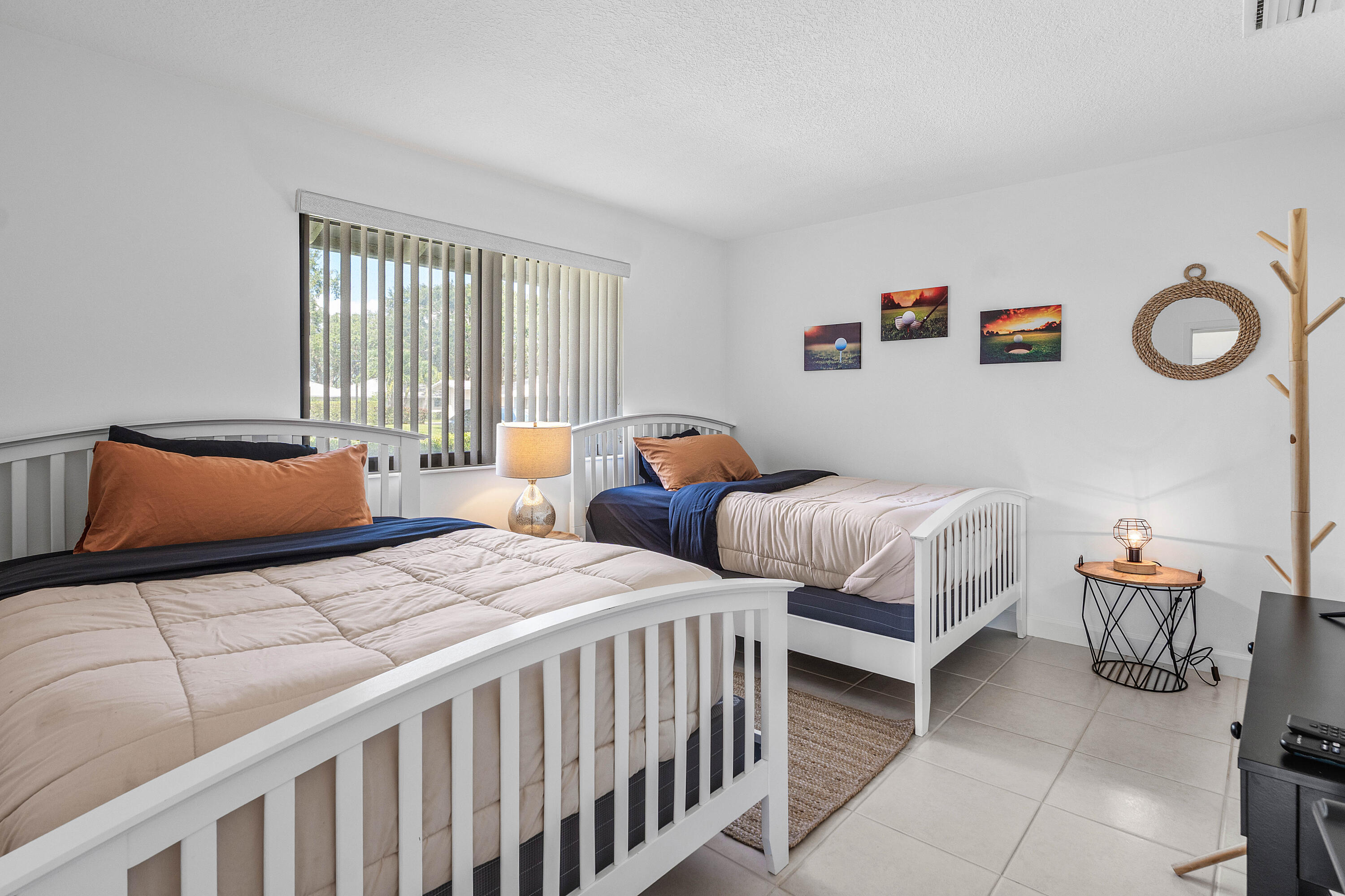 Bedroom featuring light-colored tile flooring, neutral wall tones, and a window fitted with vertical blinds