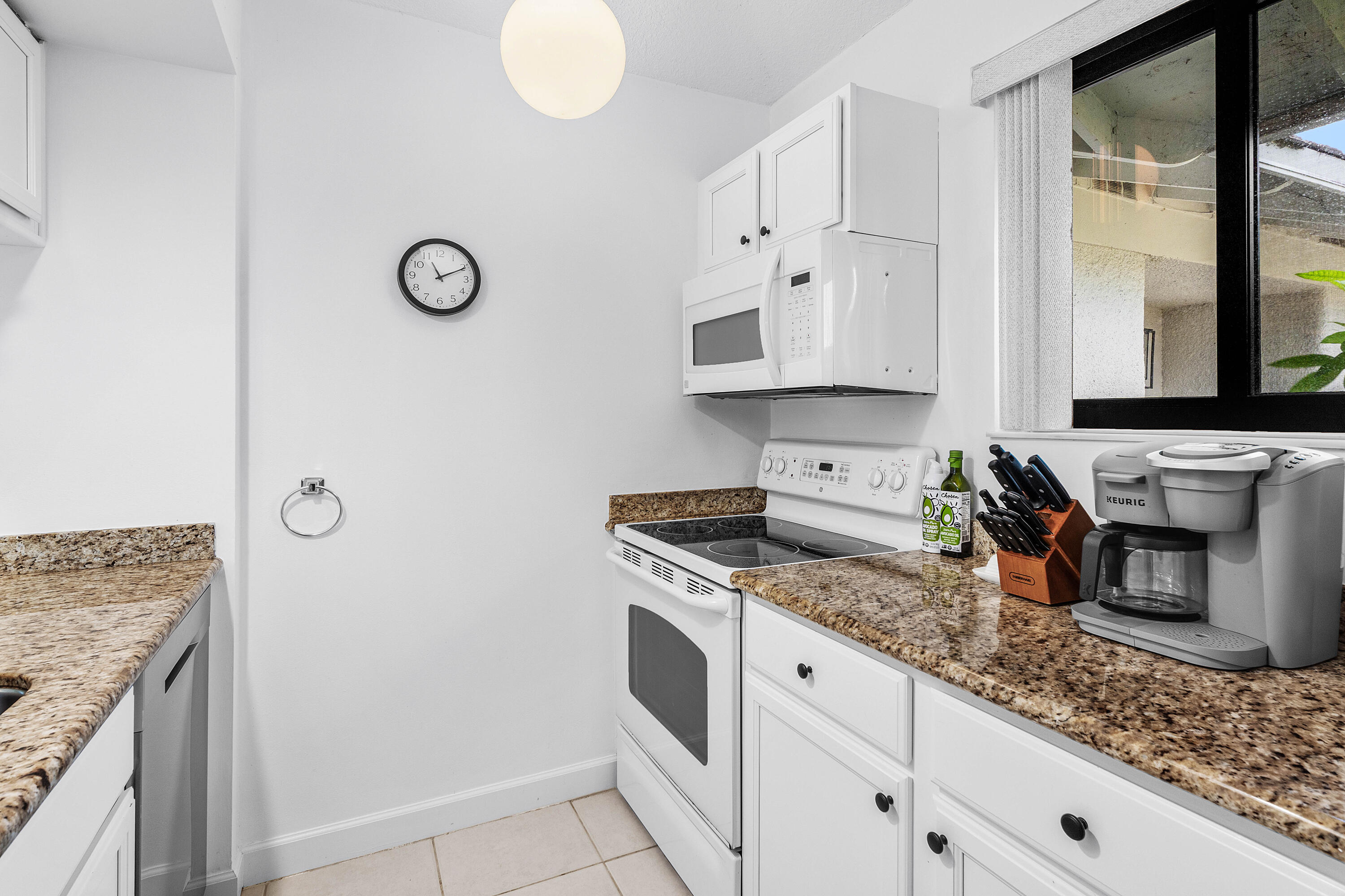 Kitchen featuring white cabinetry, stone-finish countertops, built-in microwave, integrated range, and ceramic tile flooring