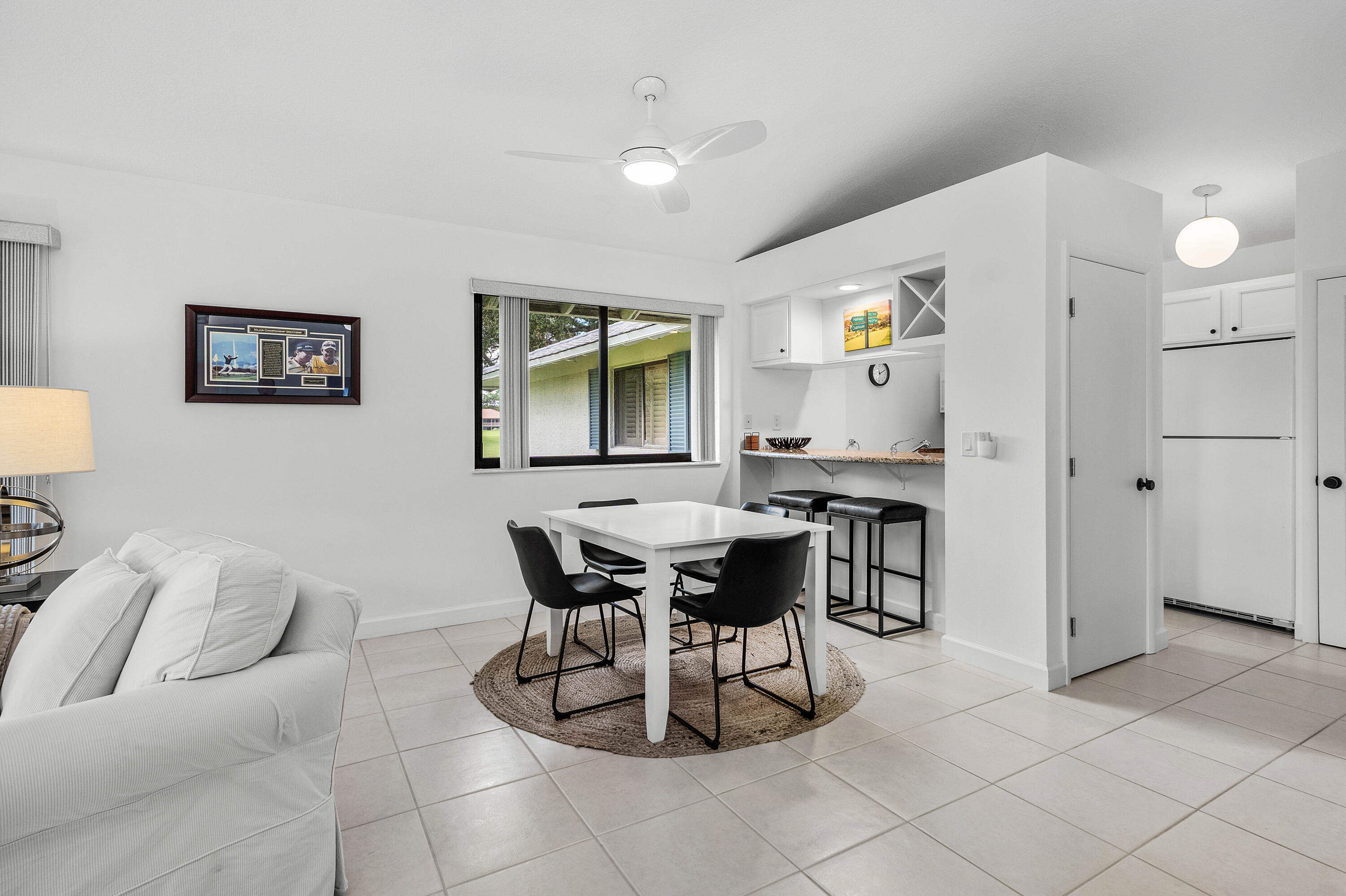 Tile flooring, integrated bar area with built-in wine rack, white cabinetry, ceiling fan with integrated lighting, and neutral wall color palette