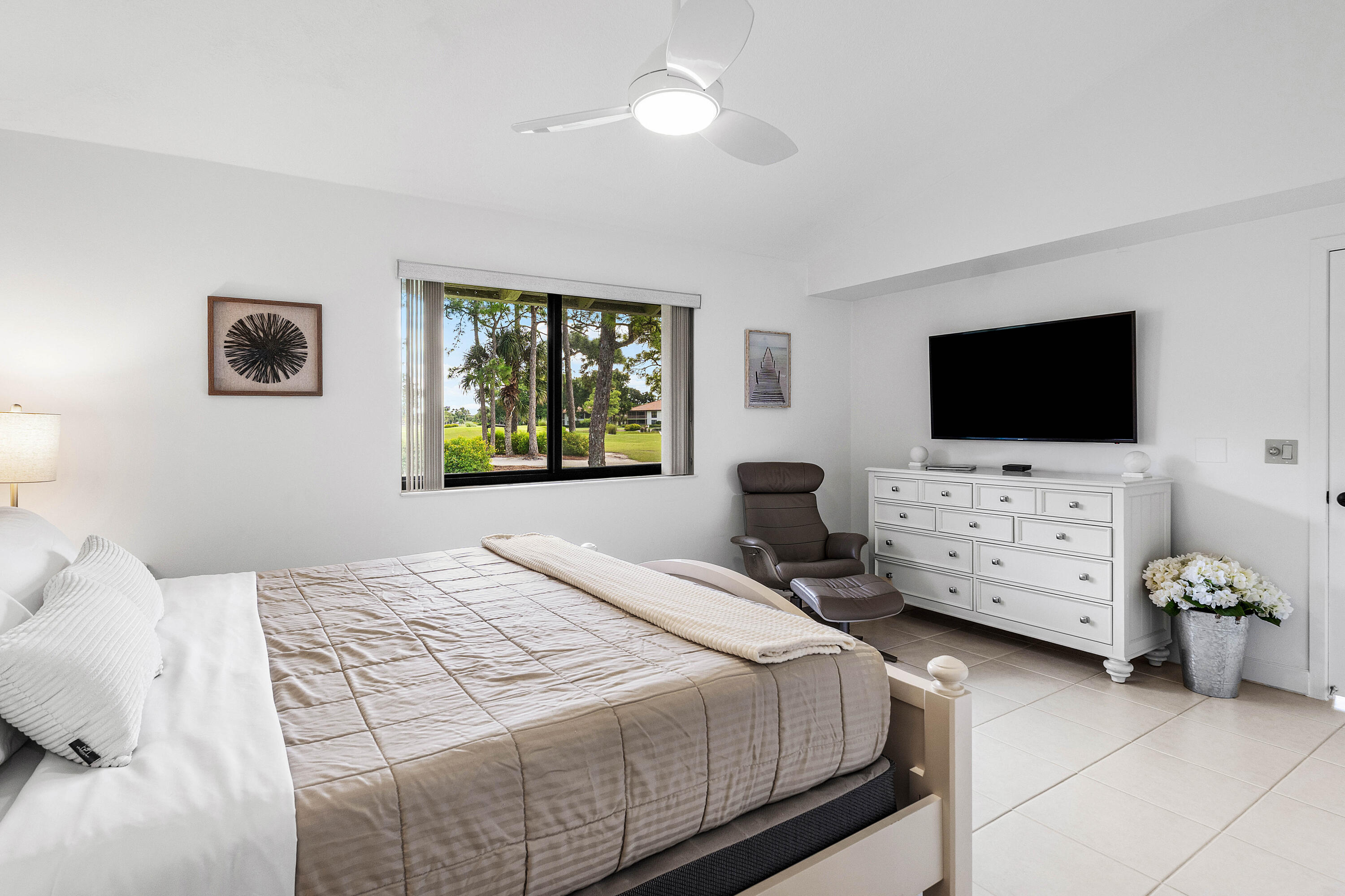 Neutral wall tones, oversized tile flooring, recessed window casing, and a multi-blade ceiling fan with integrated lighting