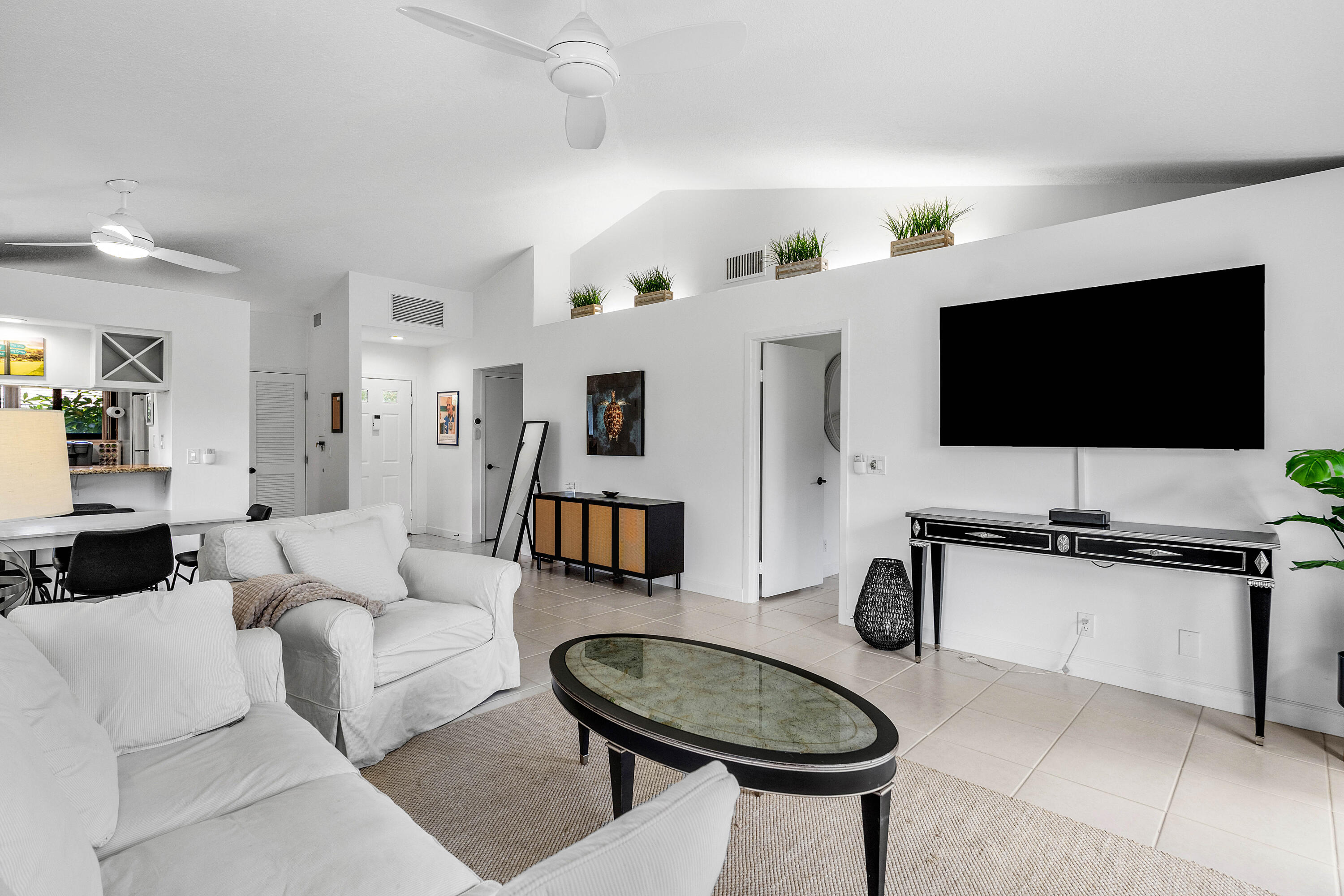 Vaulted ceilings, neutral tile flooring, recessed architectural shelving, and dual ceiling fans