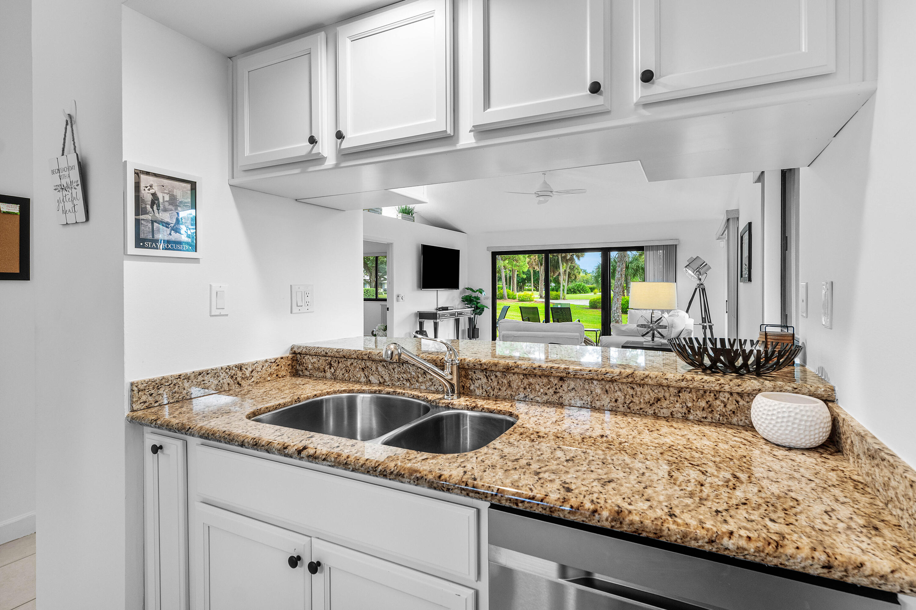 Kitchen featuring white cabinetry, stone-surface countertops, dual-basin stainless steel sink, and stainless steel dishwasher