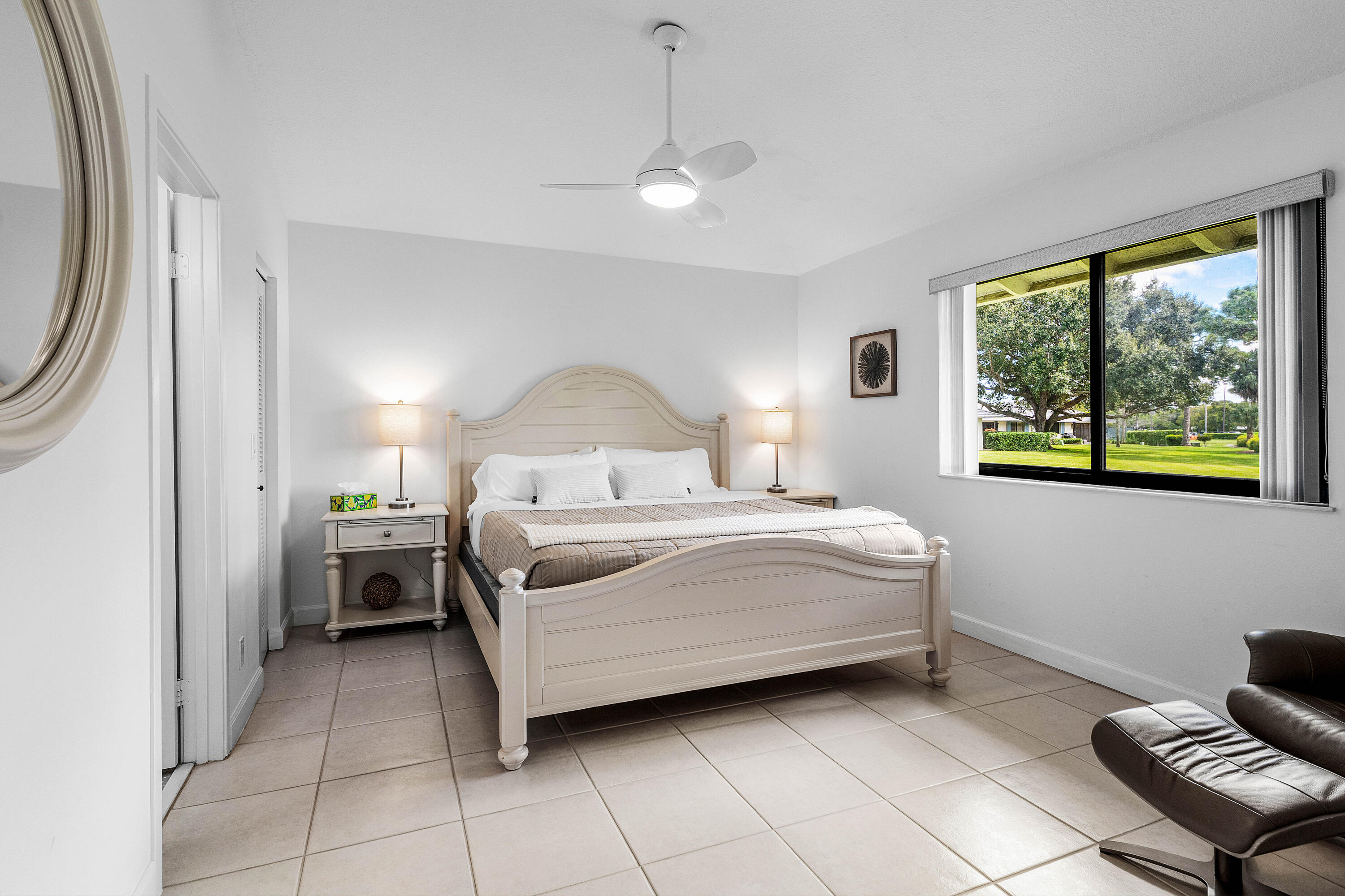 Neutral-toned ceramic tile flooring, ceiling fan with integrated lighting, and oversized window featuring a landscape backdrop