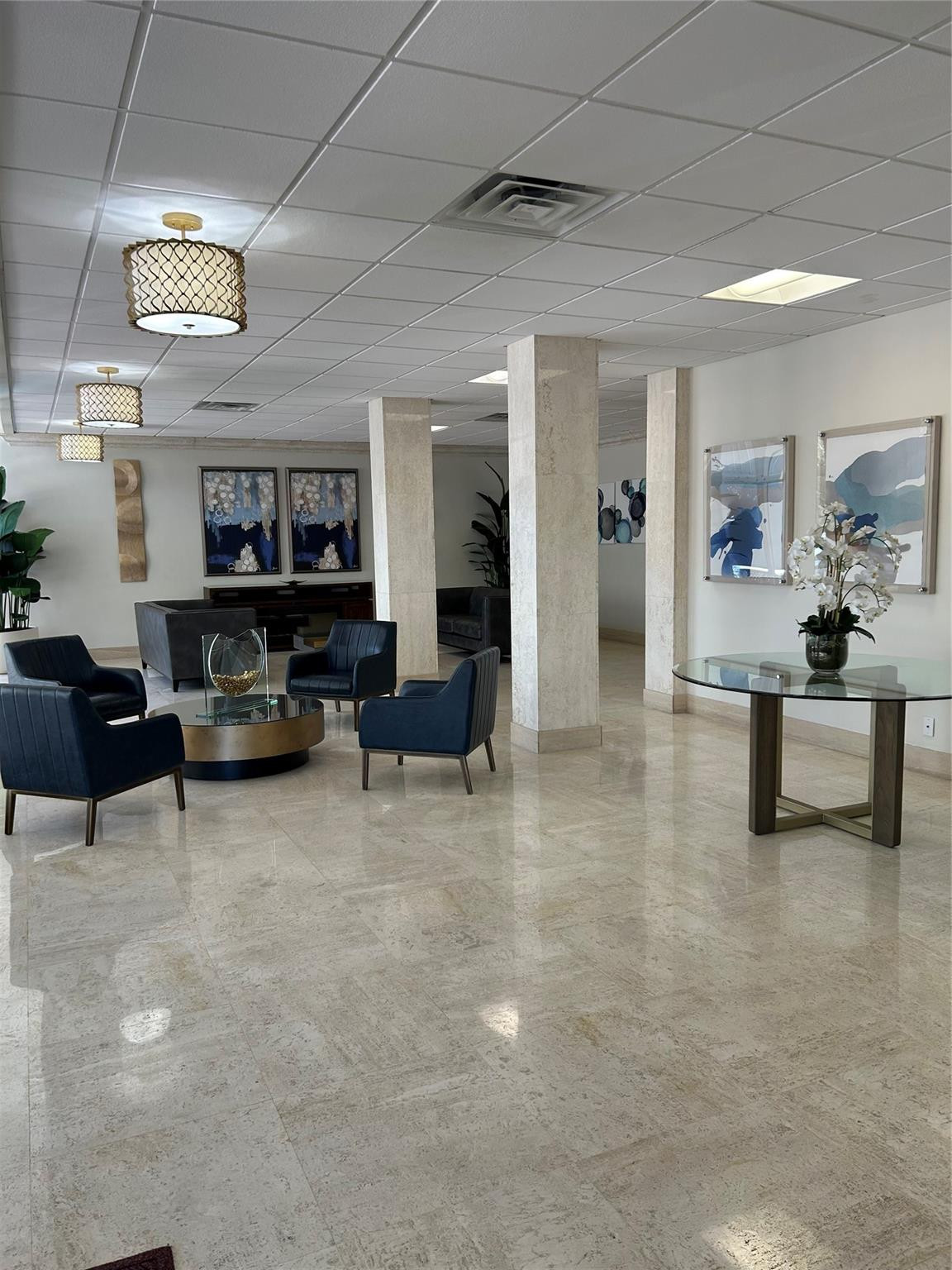 Polished stone flooring, structural columns with stone-finish cladding, and drum-style decorative lighting