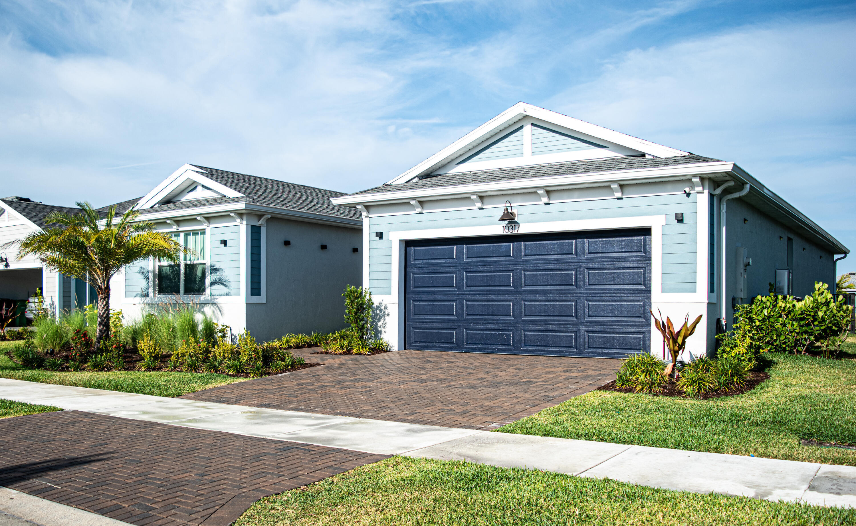 Exterior featuring lap siding, asphalt shingle roof with gable accents, carriage-style garage door, and paver driveway